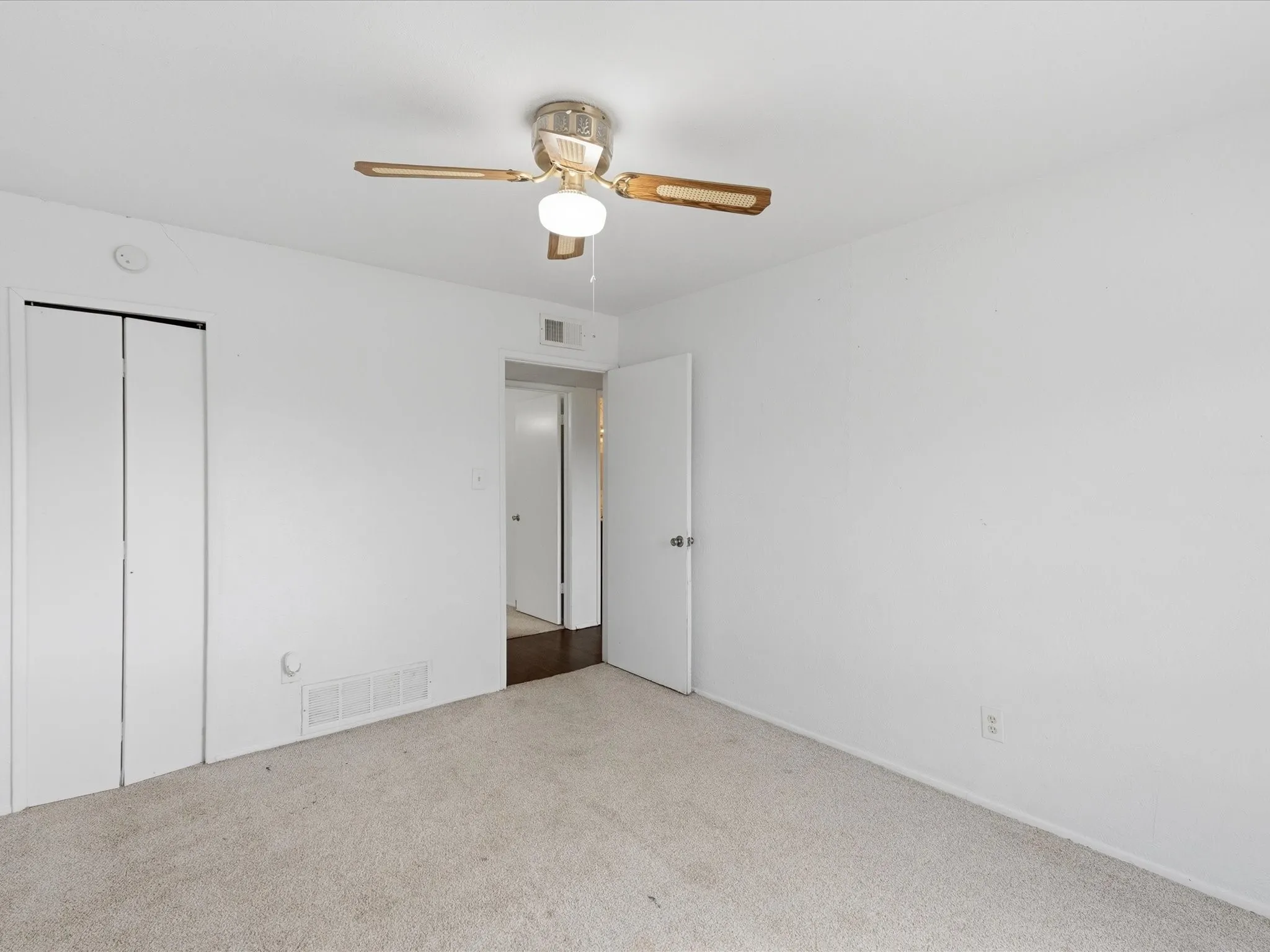 Neutral wall color, ceiling fan with integrated lighting, bi-fold closet doors, and light-toned carpeting
