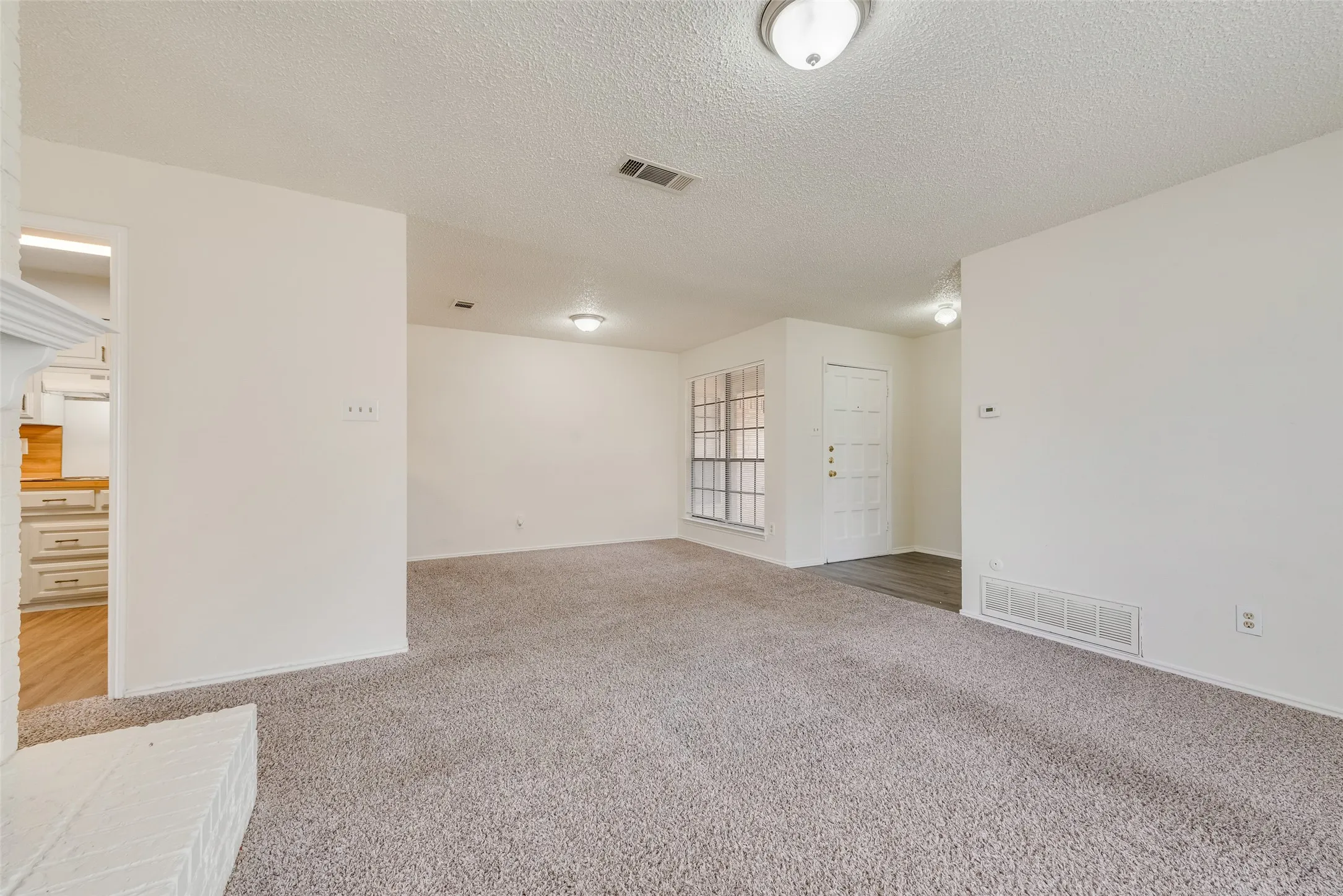 Carpeted living area with white interior paint, transom window, and flush-mount ceiling lights