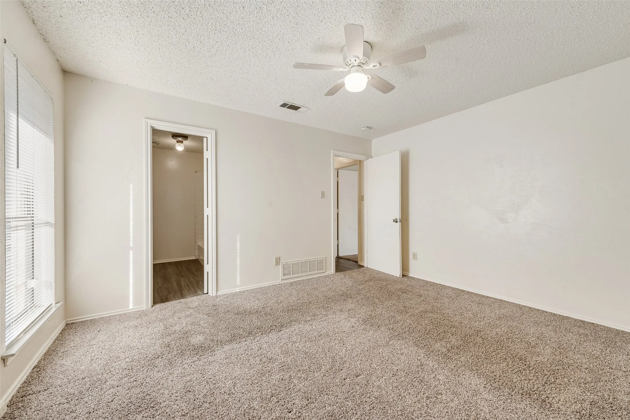 Carpeted flooring, window with blinds, ceiling fan with integrated lighting, and neutral wall tones