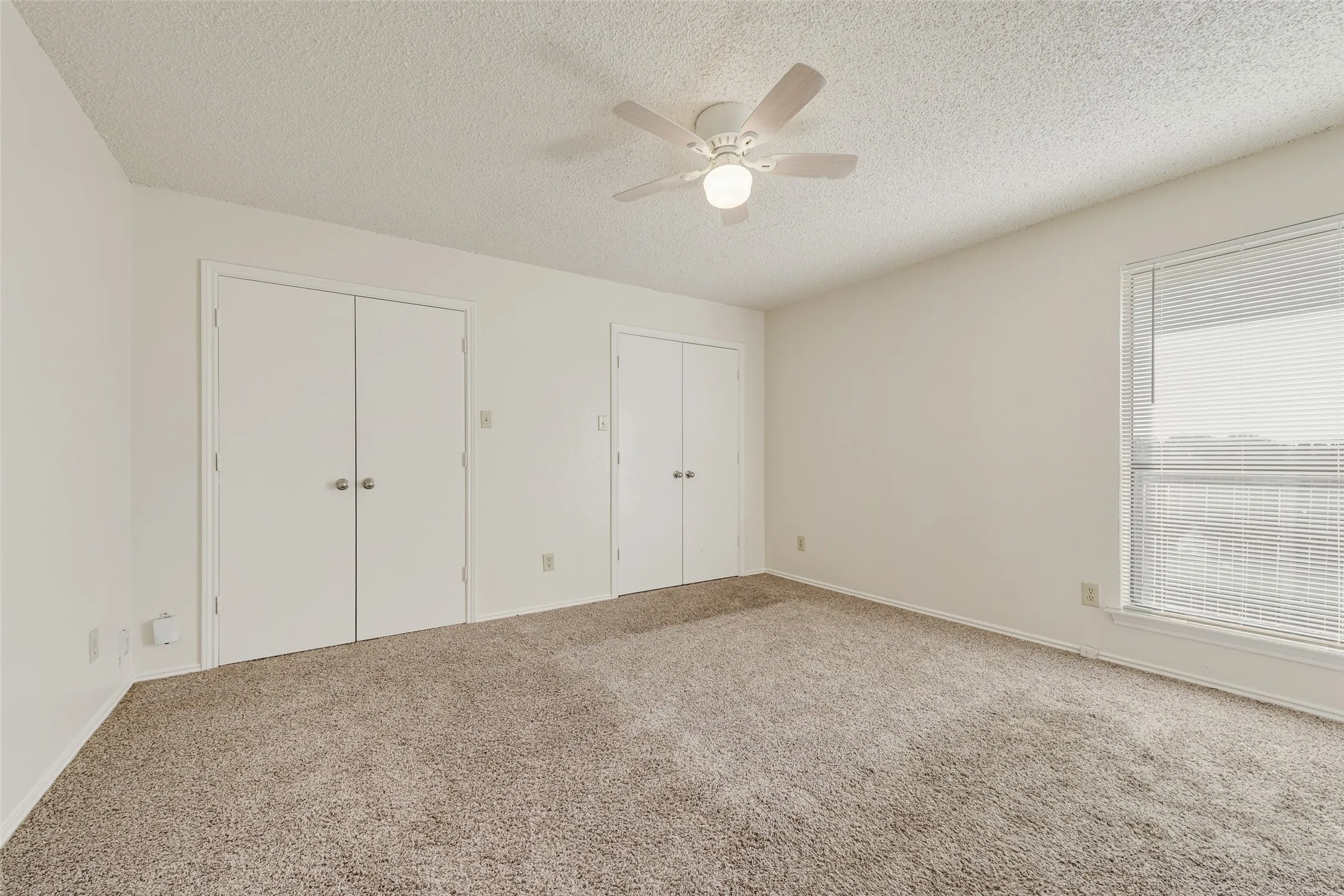 Neutral-toned carpeting, white walls, and a ceiling fan with integrated lighting