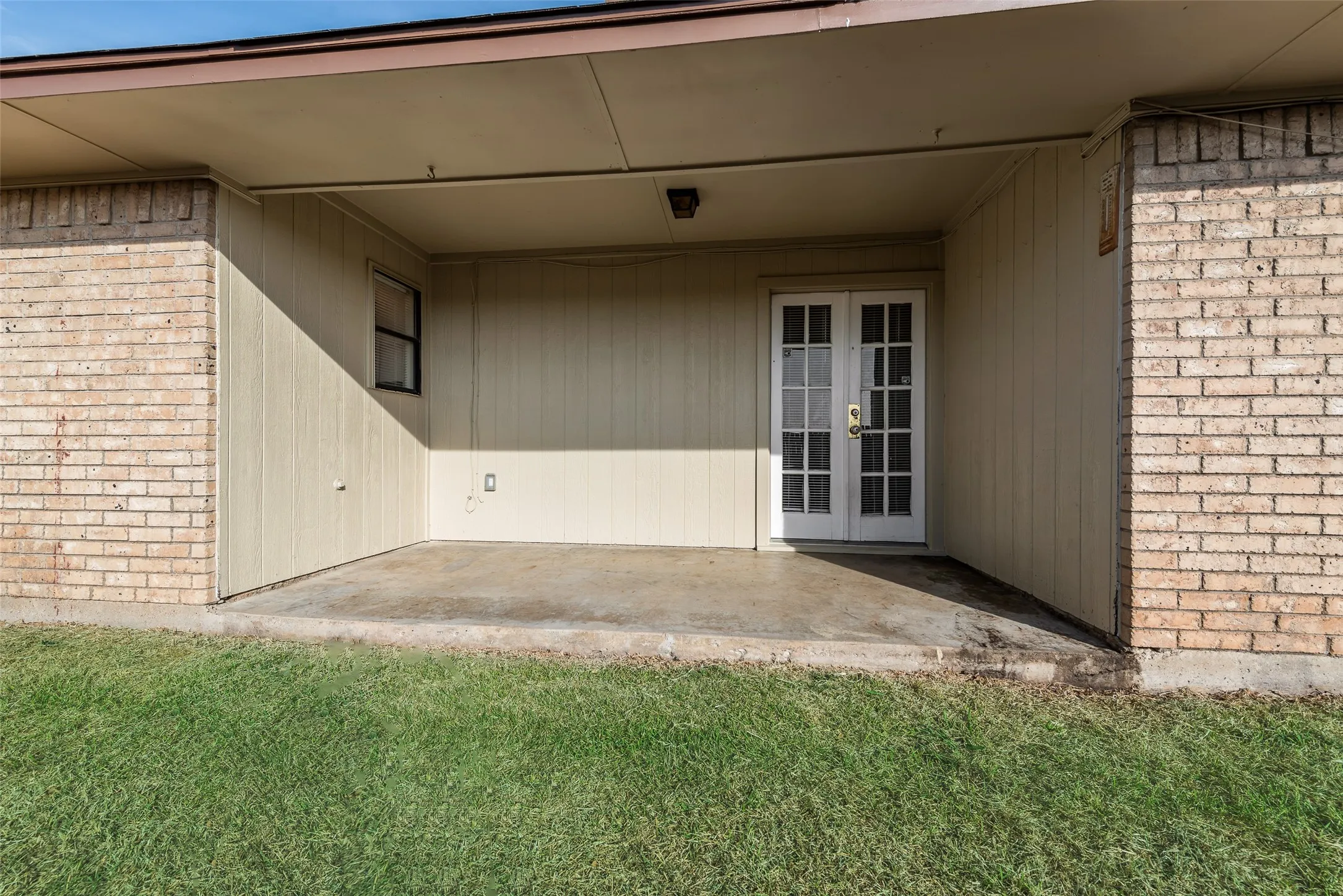Covered patio with a concrete surface, brick exterior, and French doors