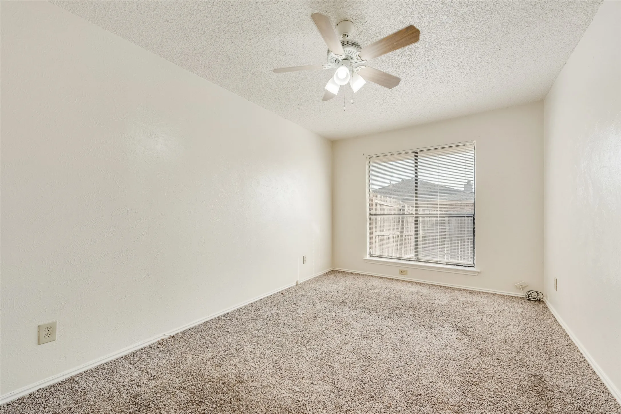 Wall-to-wall carpeting with a neutral finish, a ceiling fan with integrated lighting, and a large window with window treatments