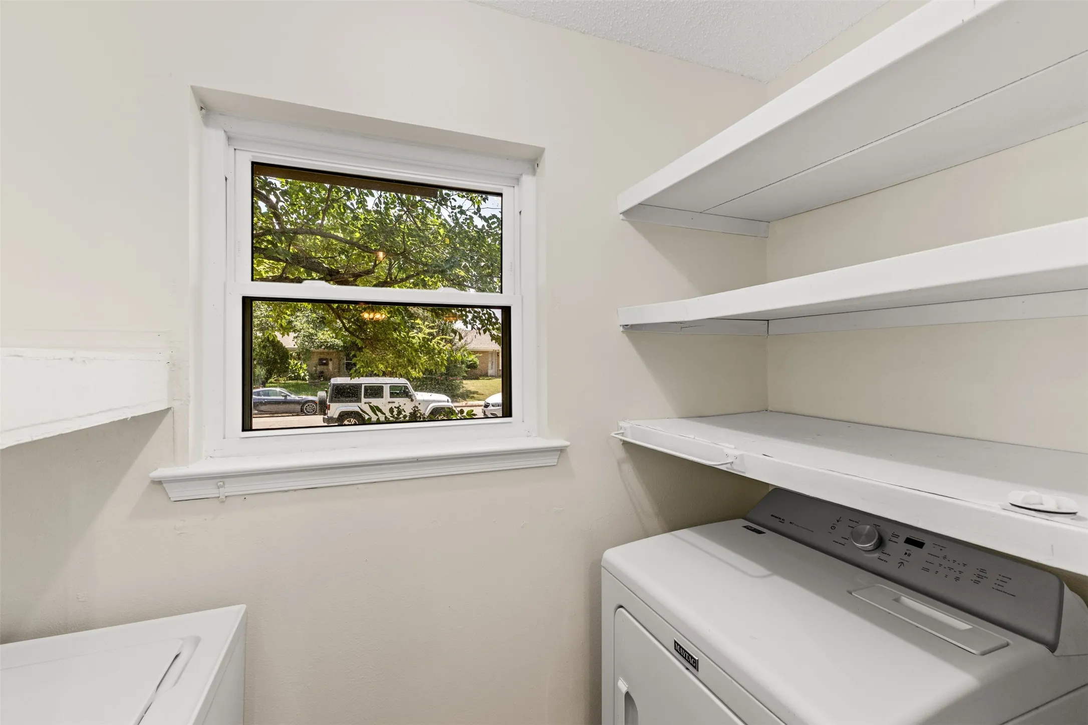 White painted walls with a single window and multiple built-in shelves