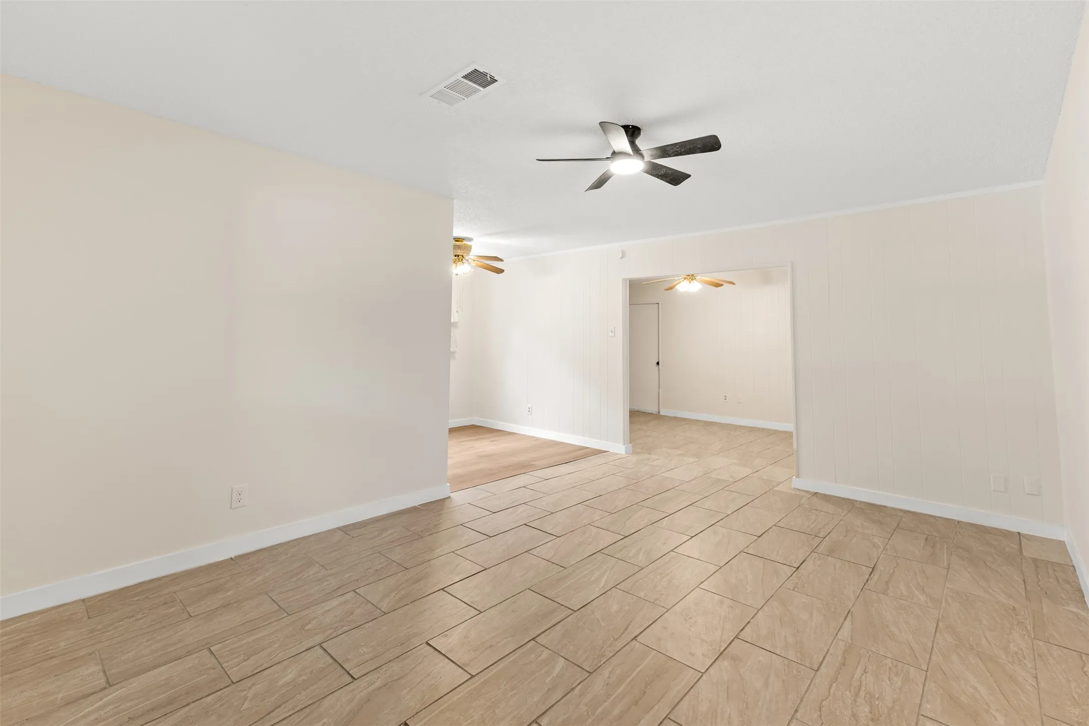 Tiled flooring, neutral wall tones, modern ceiling fan, and an open doorway