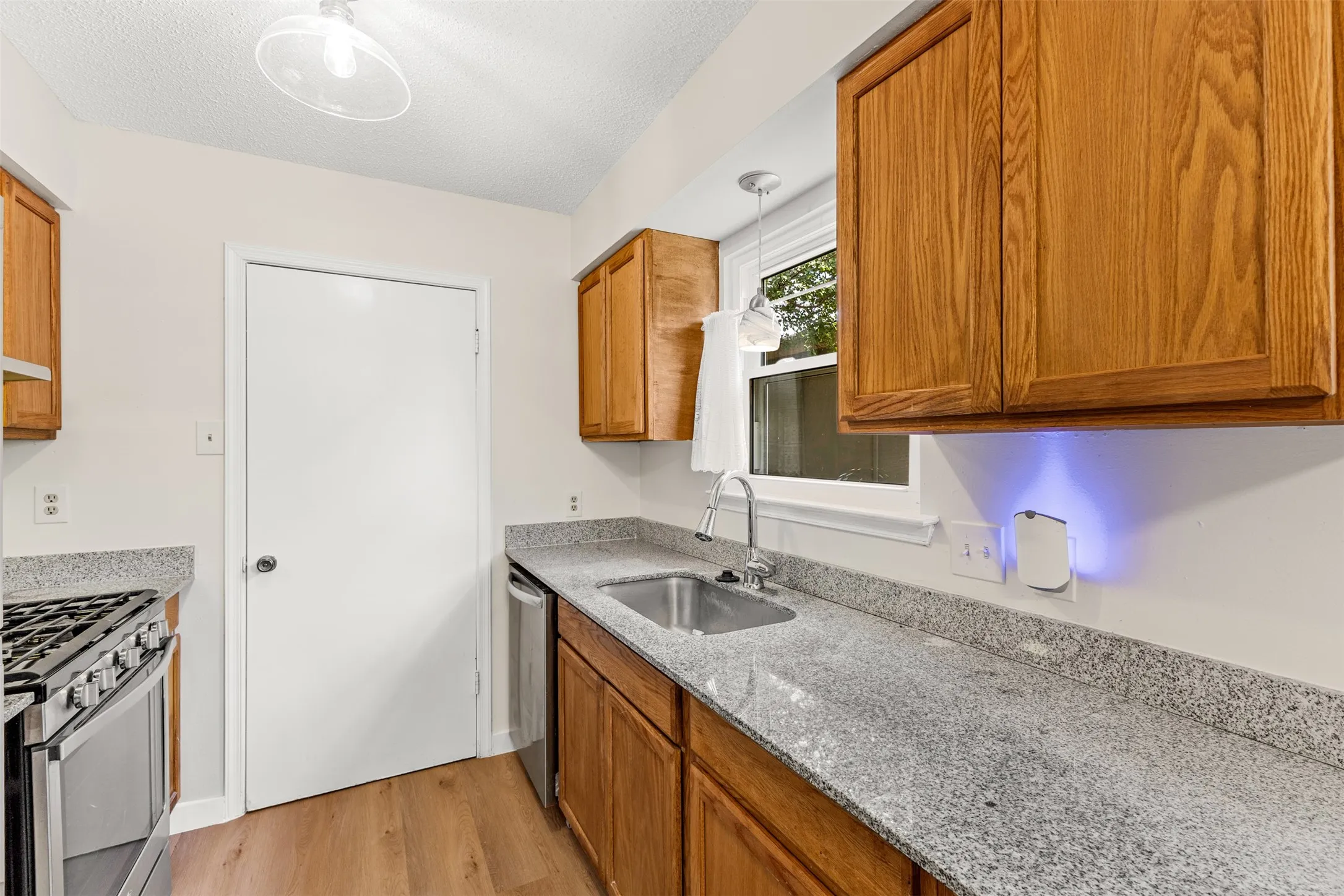 Kitchen featuring wood-finish cabinetry, light-toned countertops, and wood-finish flooring