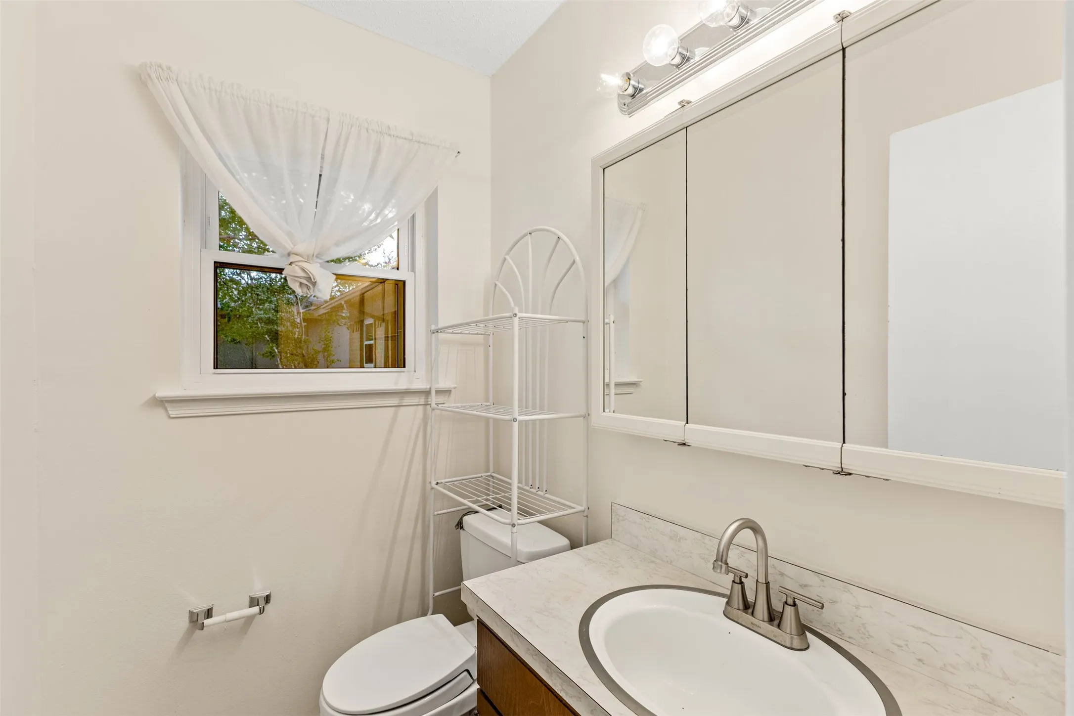Built-in vanity with an undermount sink, brushed nickel faucet, and a wall-mounted medicine cabinet with integrated lighting