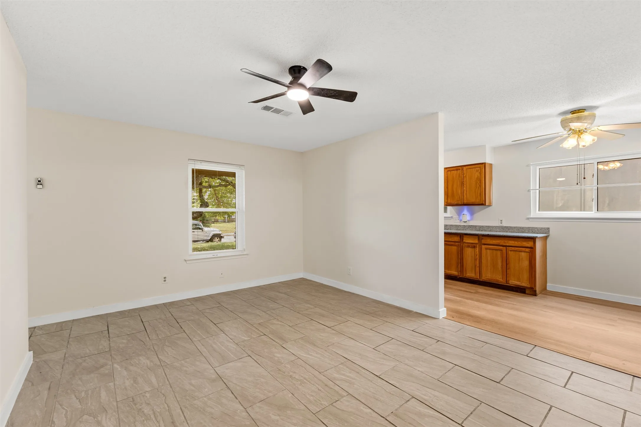 Tiled flooring, neutral wall tones, modern ceiling fan, and an open doorway to kitchen