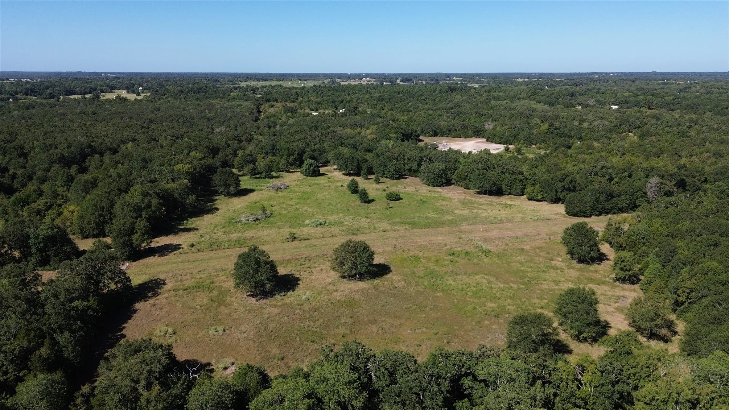 Expansive cleared areas, mature trees, and natural wooded surroundings