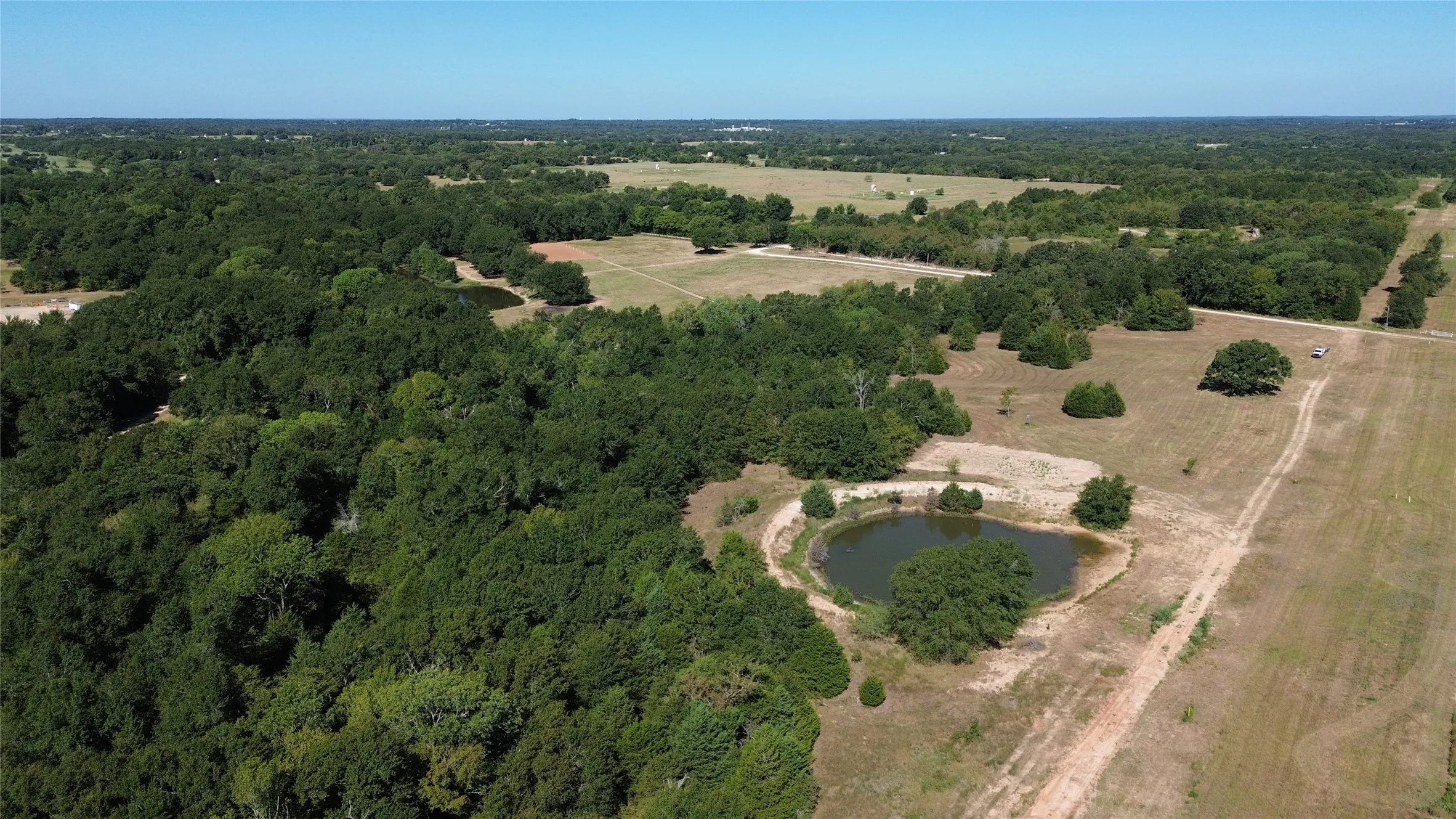Expansive acreage featuring a natural pond, wooded areas, and open fields