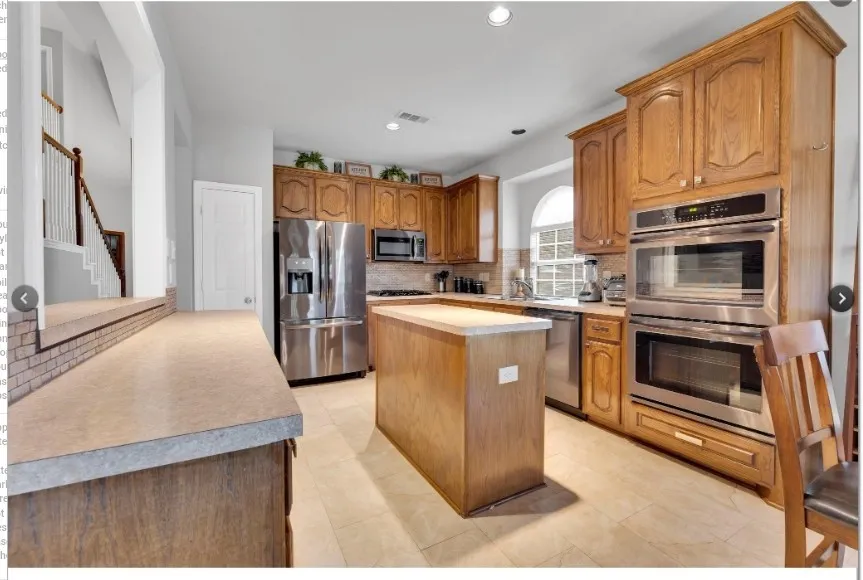 Wood-finish cabinetry, stainless steel appliances, central island, and tiled flooring