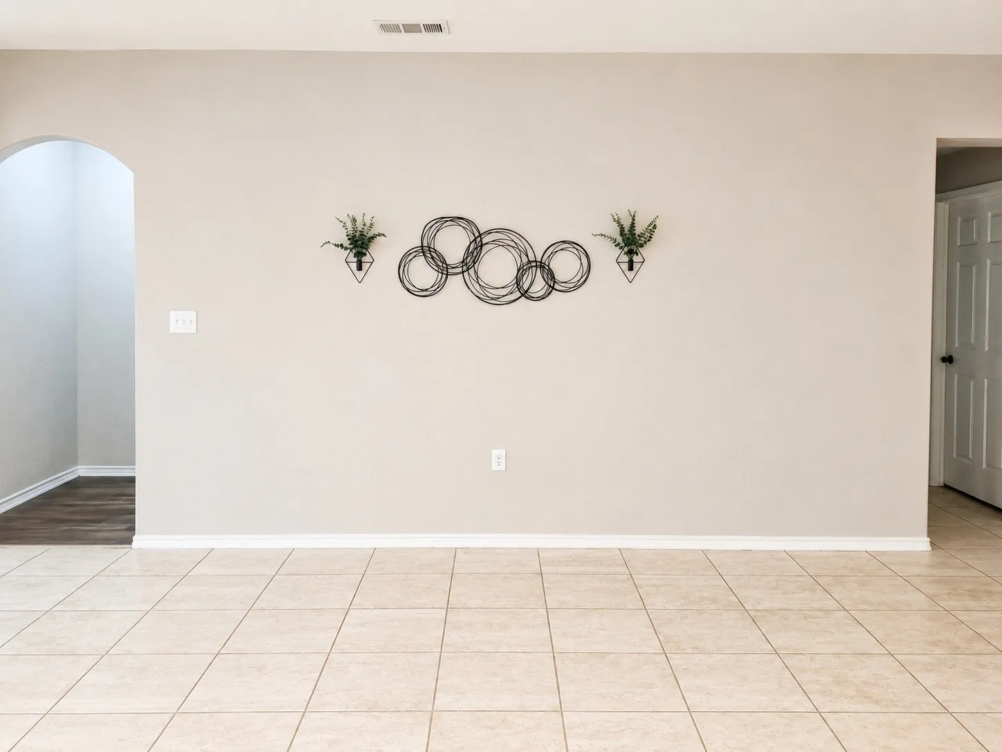 Tile flooring, neutral wall tones, arched doorway, panel door with dark hardware