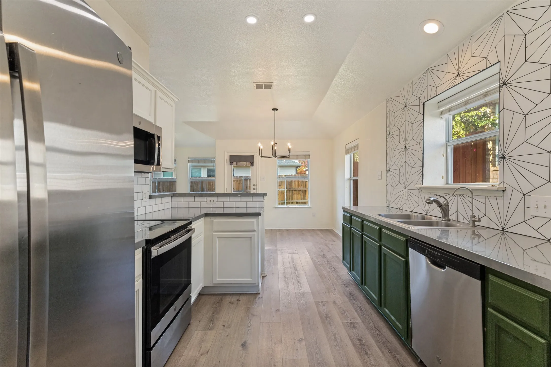 Kitchen featuring stainless steel appliances, wood-finish flooring, recessed lighting, and a decorative tile backsplash