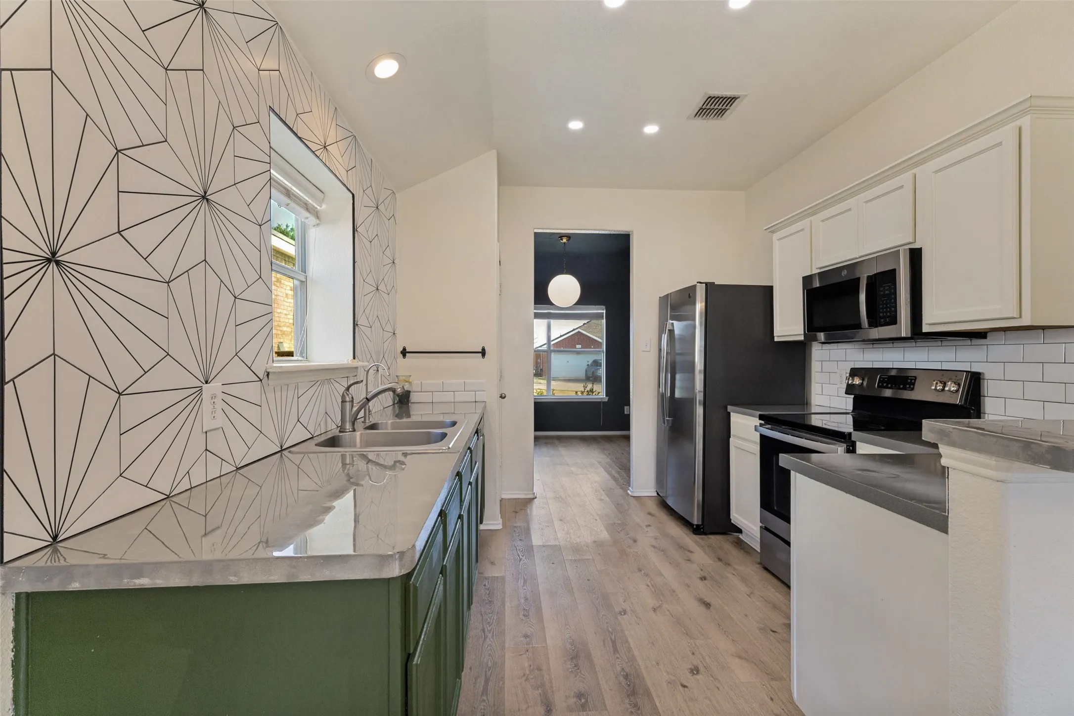 Kitchen featuring stainless steel appliances, wood-finish flooring, recessed lighting, white subway tile backsplash, and decorative accent wall tile