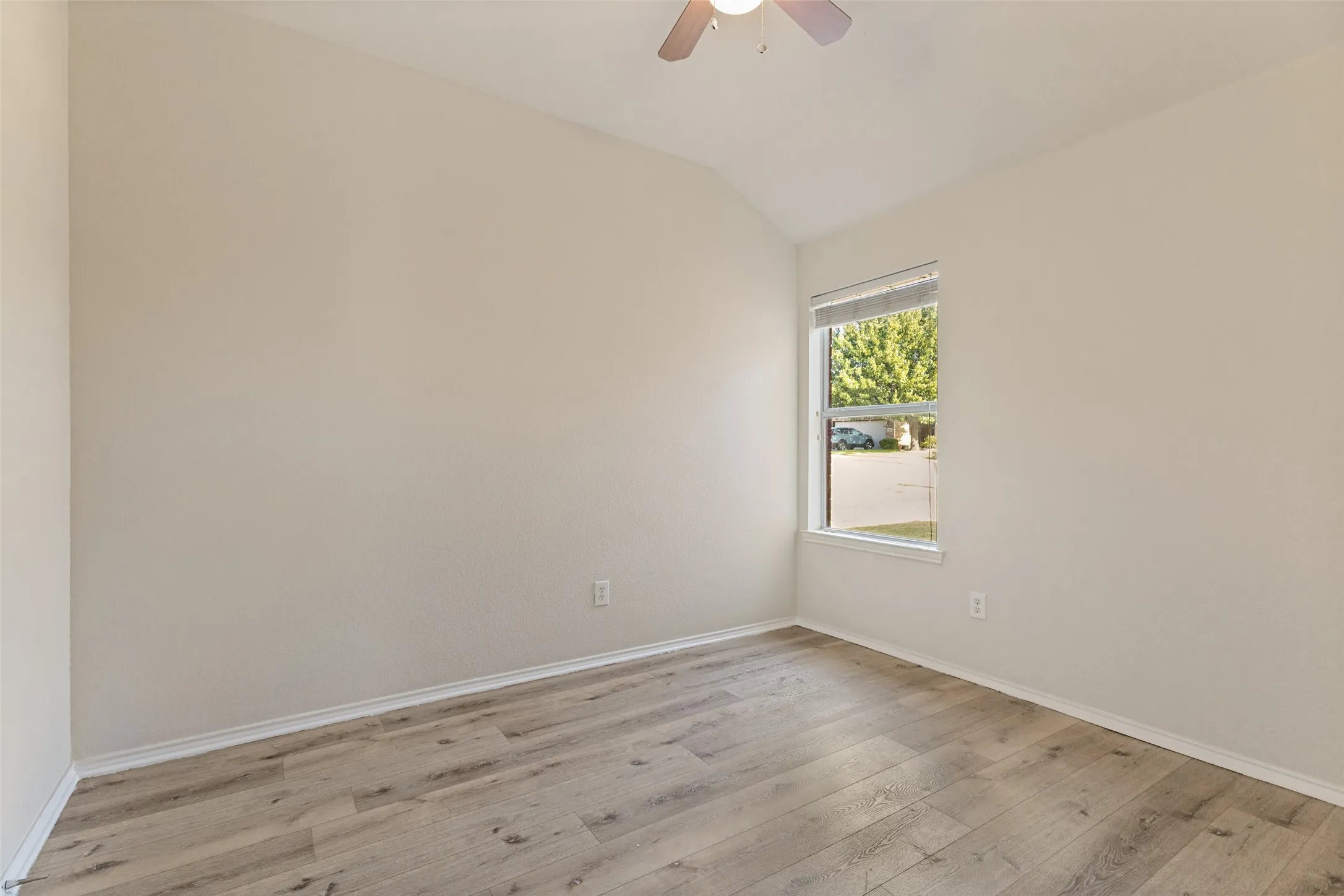 Vaulted ceiling, wood-finish flooring, single window with blinds, ceiling fan