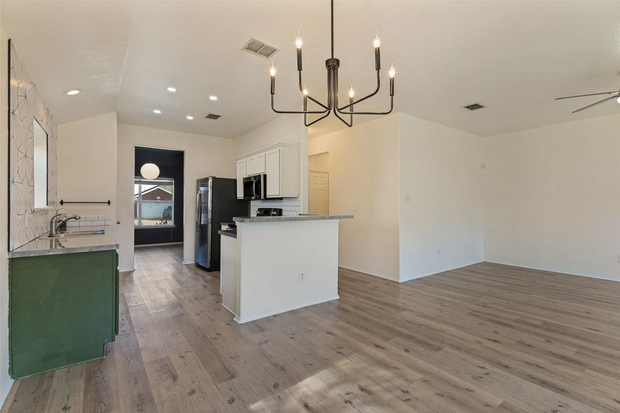 Open-concept living space featuring wood-finish flooring, a modern chandelier, a ceiling fan, and recessed lighting