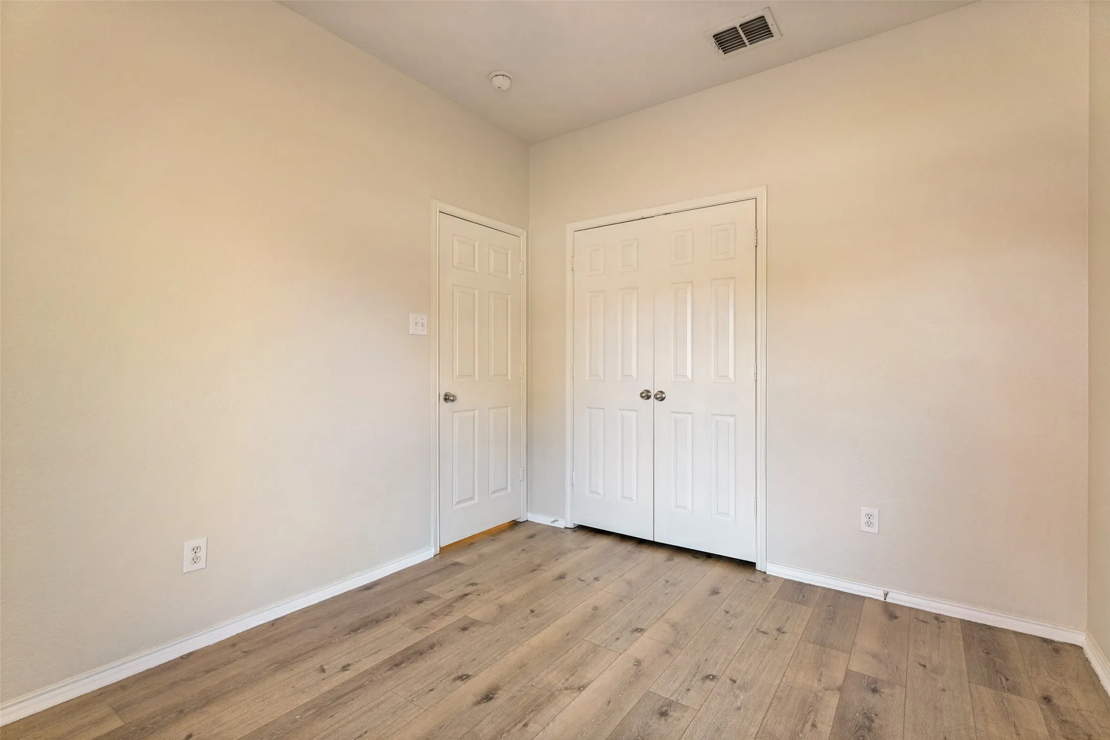 Wood-finish flooring, white walls, and a recessed ceiling light