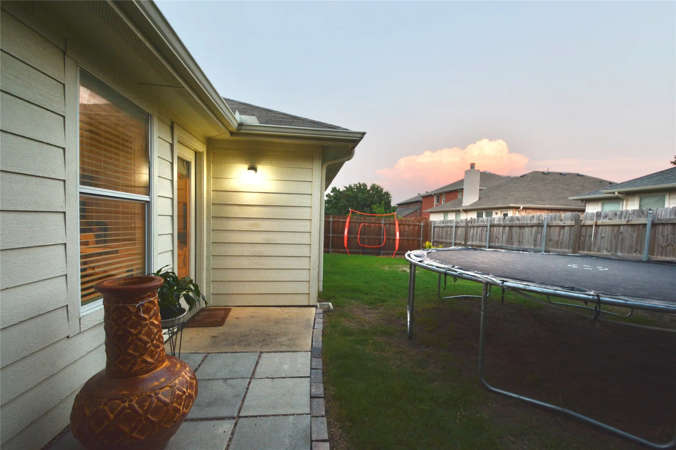 Siding exterior with a covered patio, paved walkway, and private fenced yard