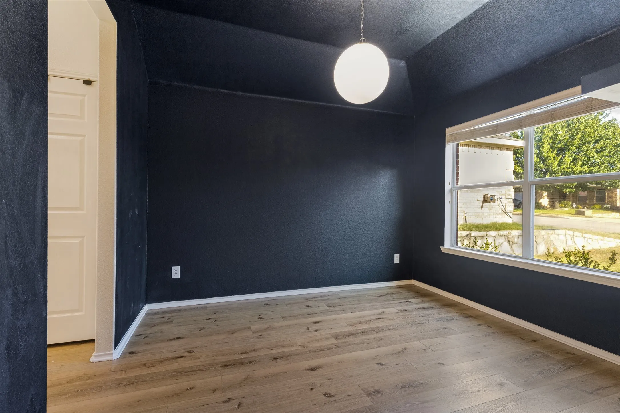 Wood-finish flooring, white trim, and a prominent window