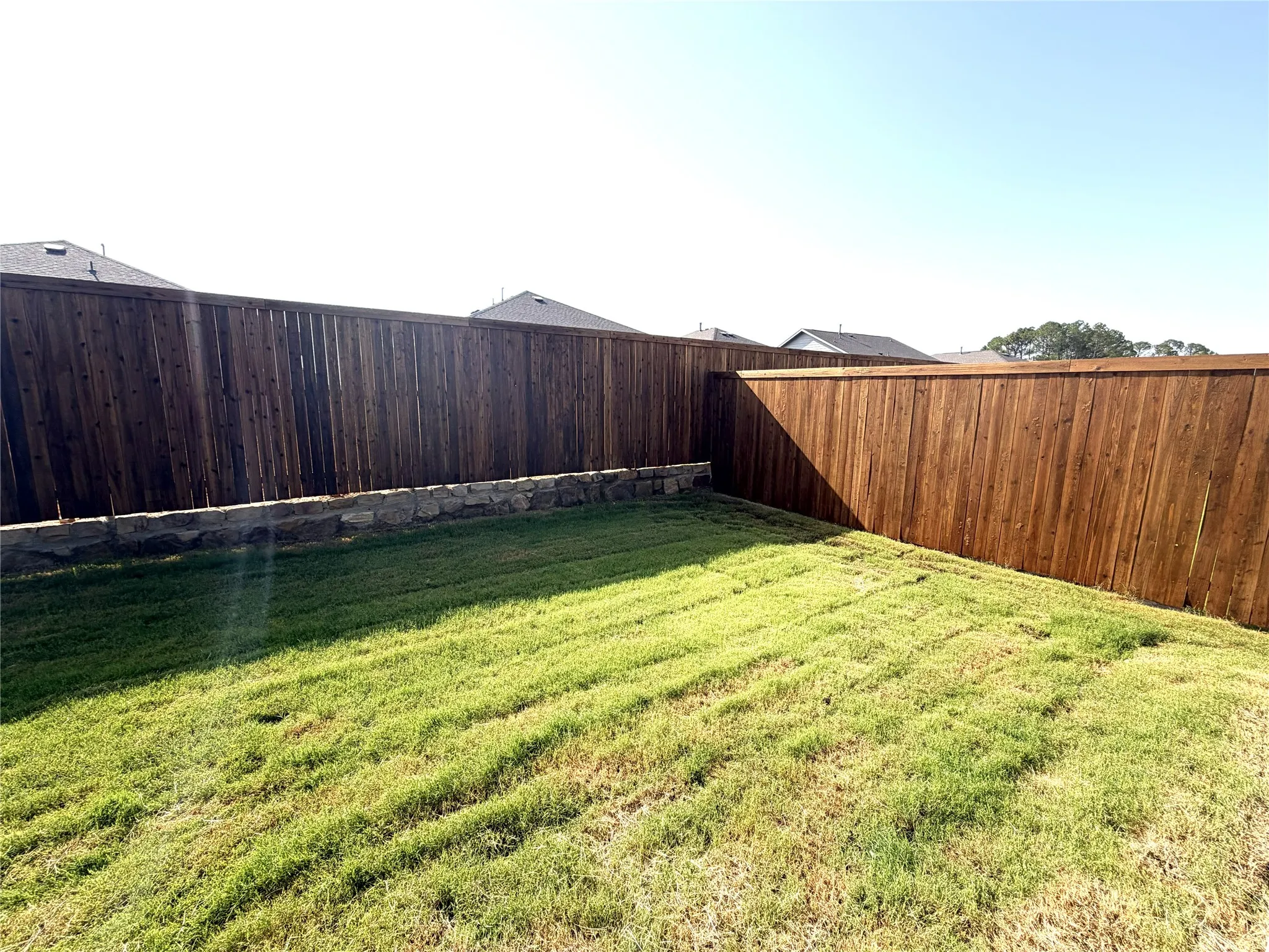 Manicured lawn, wood privacy fencing, and a stone retaining wall