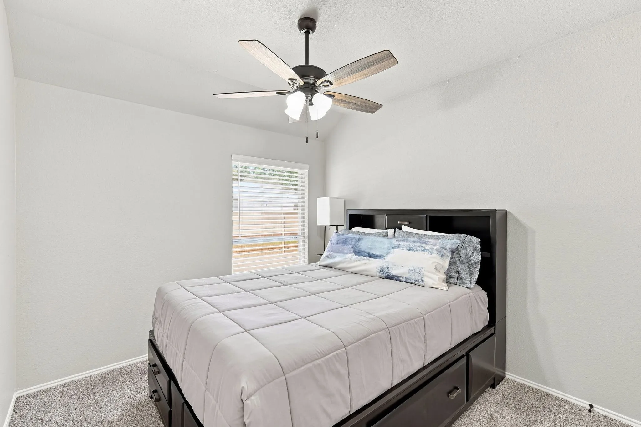 Second bedroom with neutral paint, ceiling fan and fresh carpet.