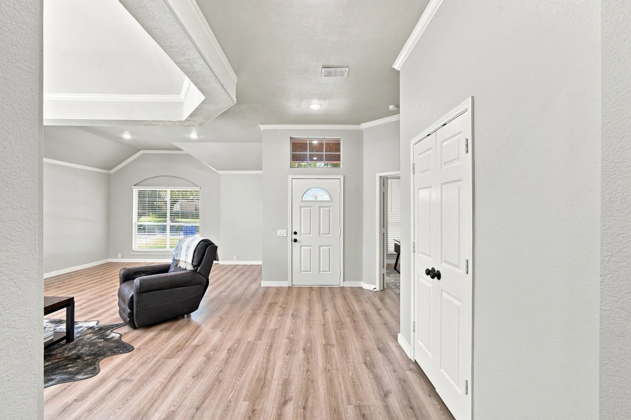 Foyer opens to formal living space.  Functional multi-use space boasts fresh neutral paint, crown molding and coffered ceiling.