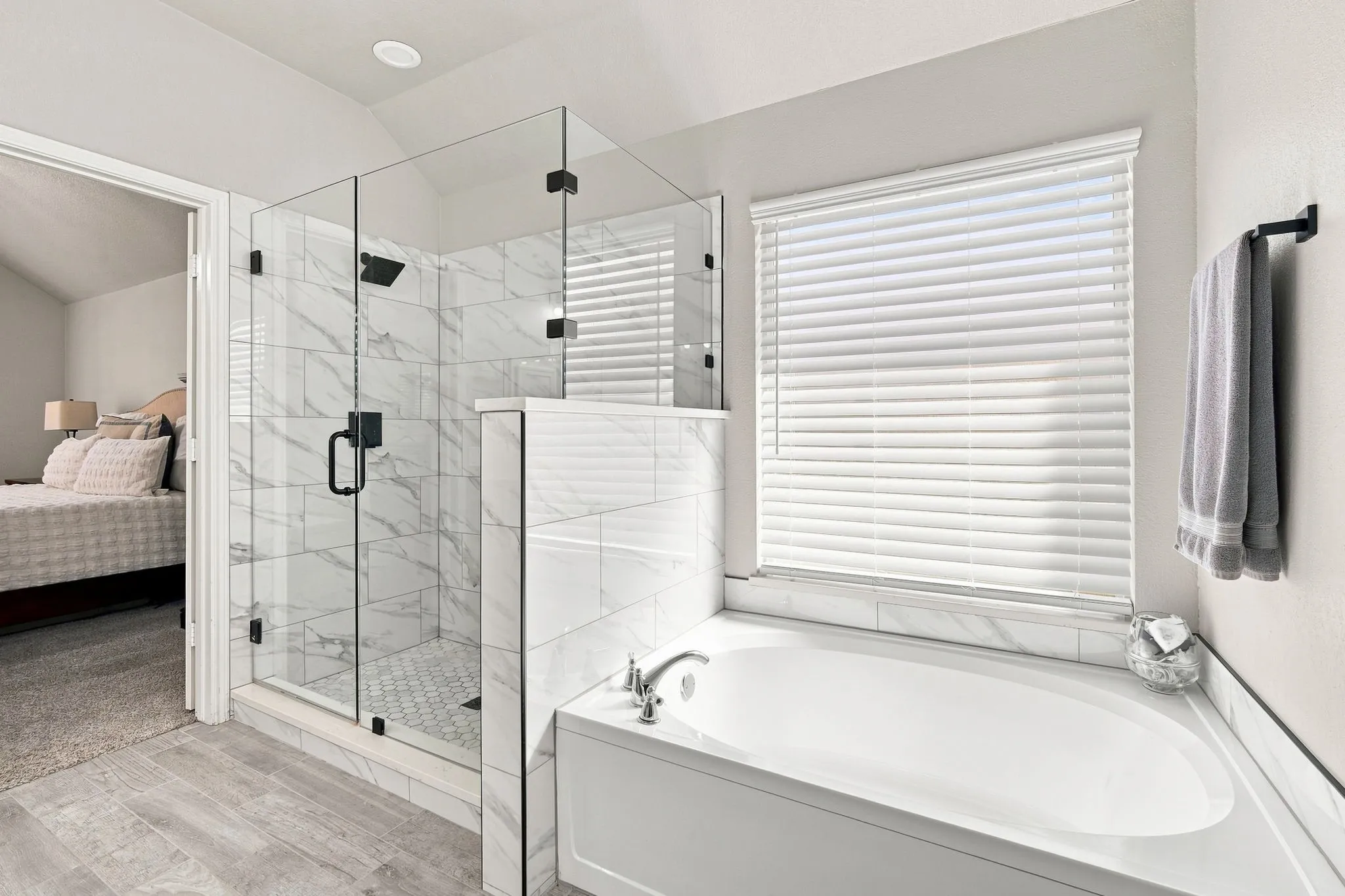 Extended shower with designer tile walls, floor and frameless glass doors accent the primary bathroom.