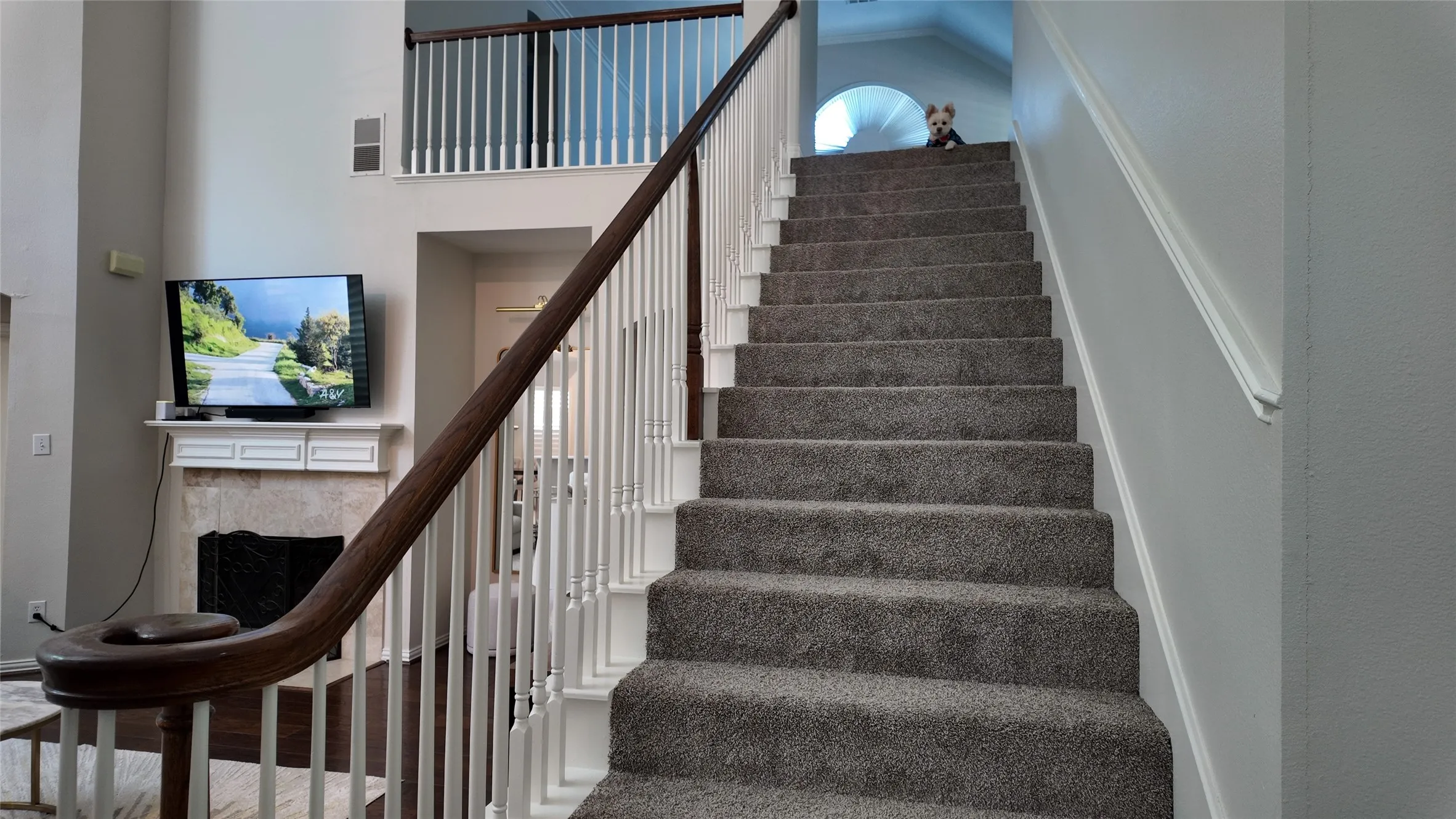 Two-story interior with a carpeted staircase, wood banister, and a white balustrade