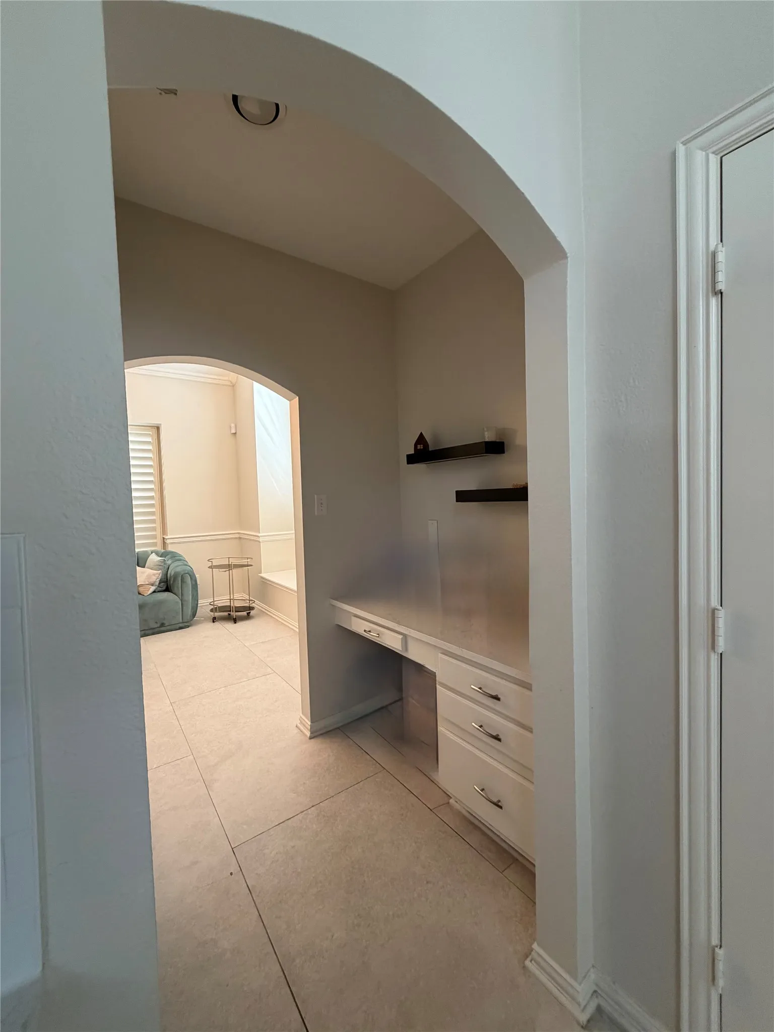 Built-in desk with three drawers, two floating shelves, recessed lighting, and tile flooring