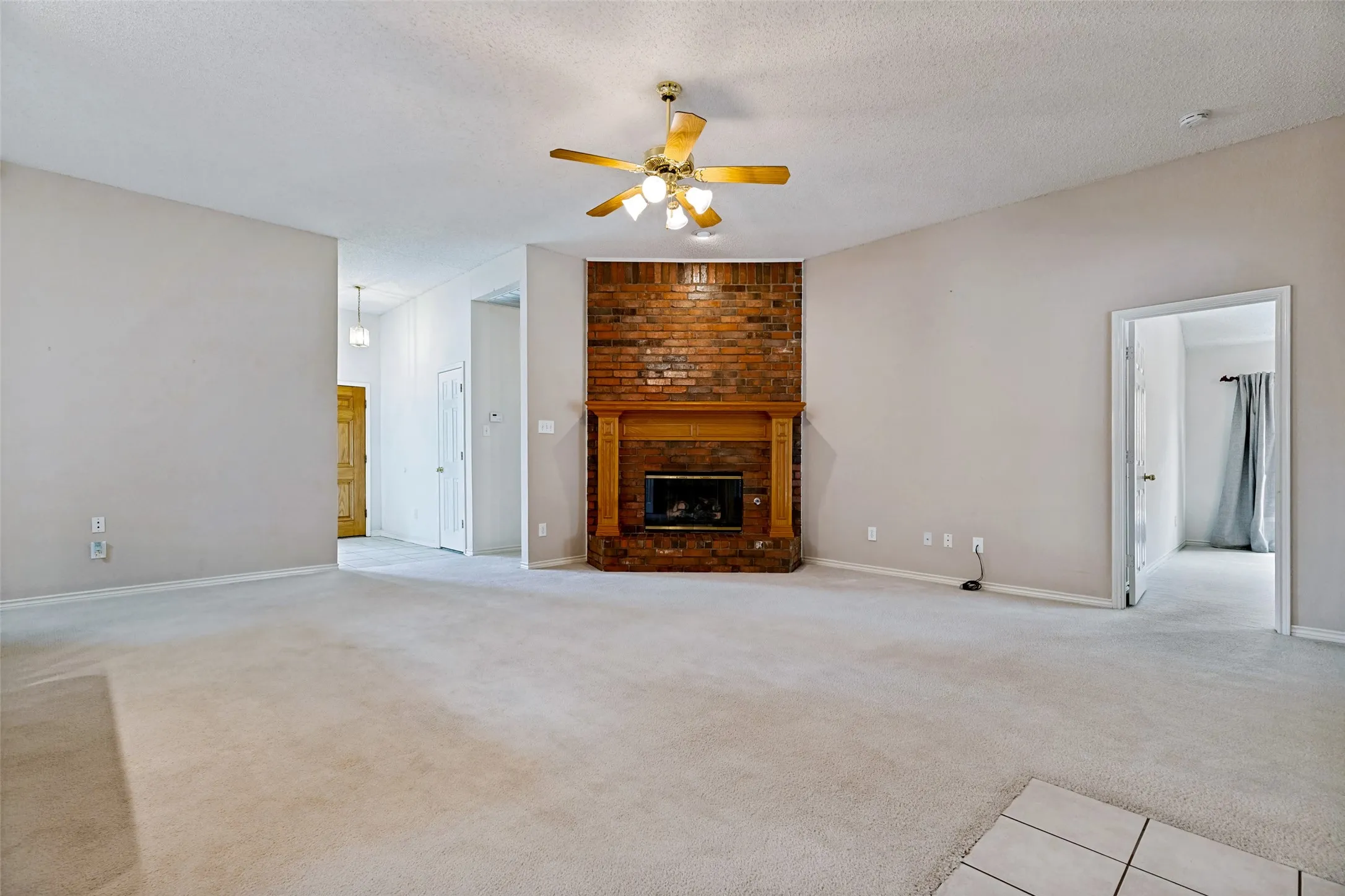 Spacious living area anchored by a striking brick fireplace with wood mantel and hearth