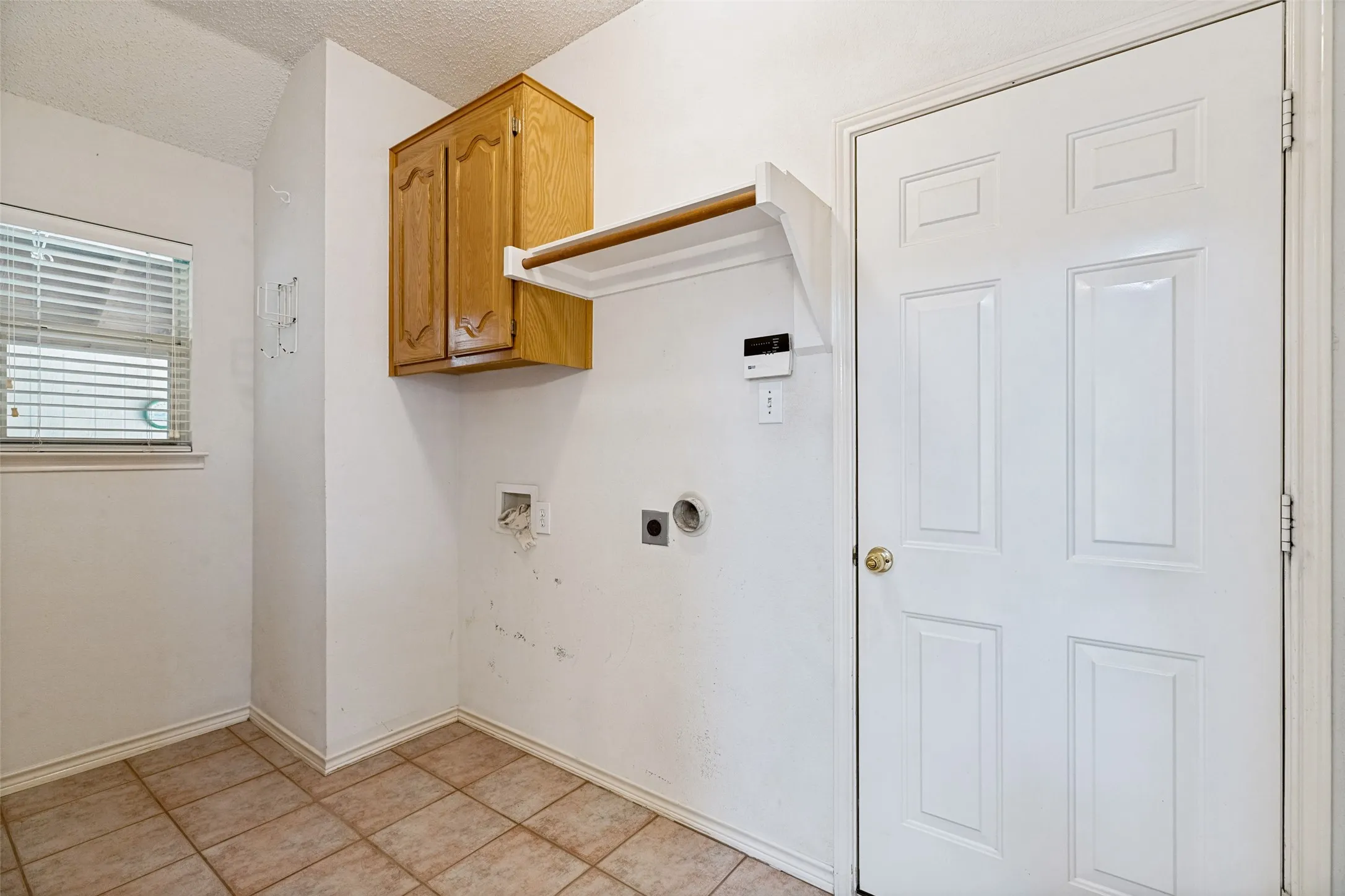 Utility room featuring wood-finish cabinetry with open shelving, tile flooring, and connections for washer/dryer hookups