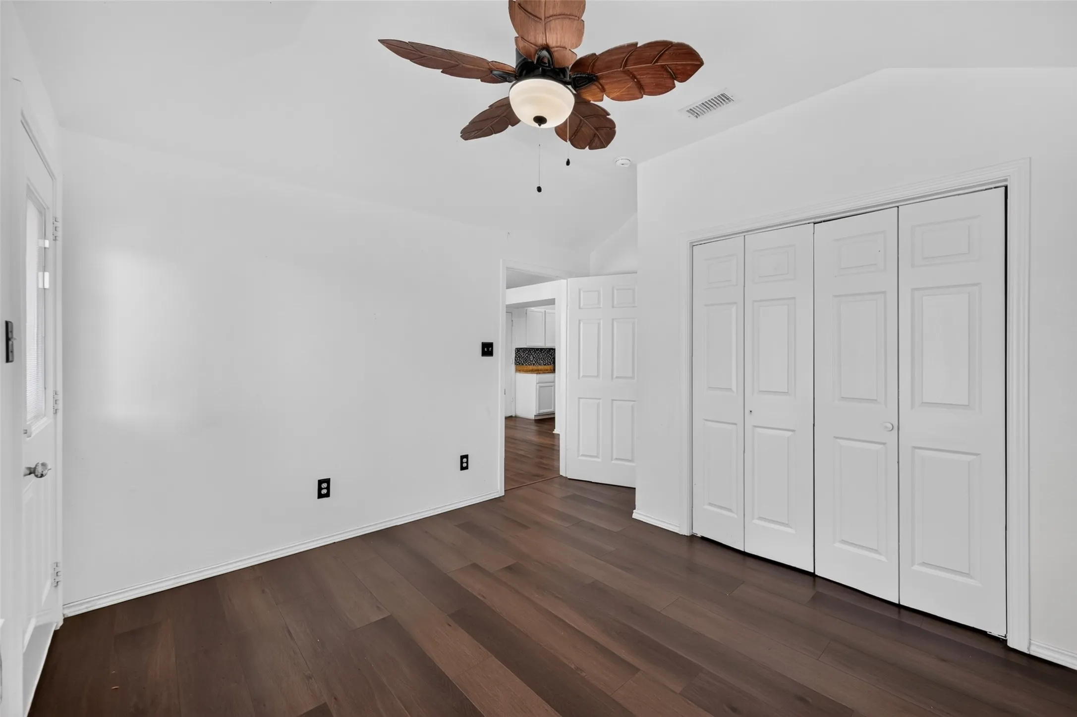 Vaulted ceiling featuring a ceiling fan, wood-finish flooring, and white bifold closet doors