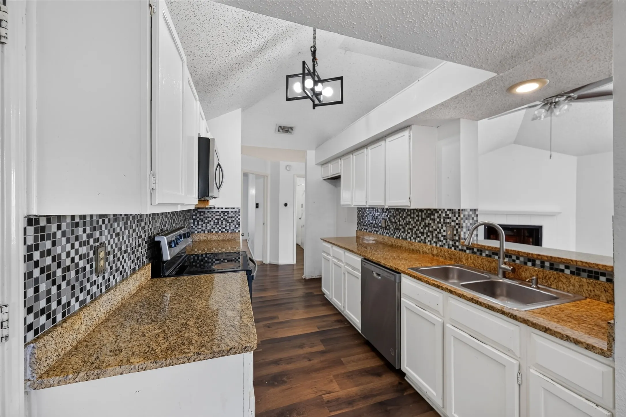 Kitchen featuring white cabinetry, granite-finish countertops, checkerboard mosaic tile backsplash, wood-finish flooring, and stainless steel appliances