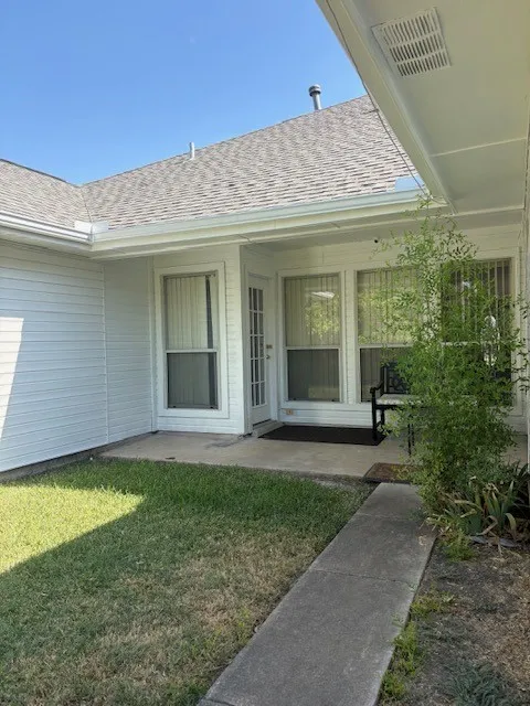Covered patio with a paneled exterior door and two adjacent windows