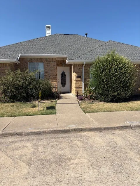 Brick exterior with an asphalt shingle roof, white trim, and a decorative oval glass front door