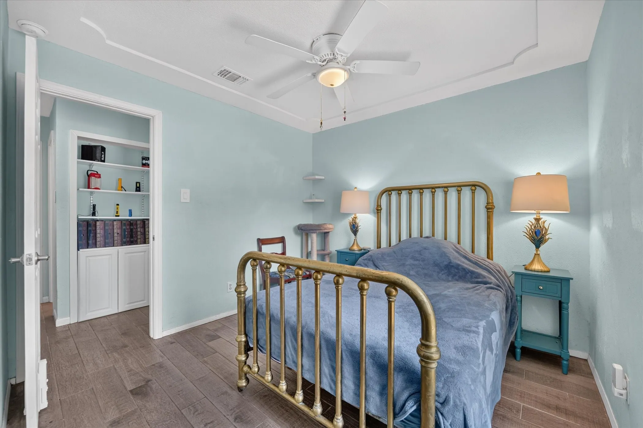 Crown molding, ceiling fan with integrated lighting, wood-finish flooring, built-in shelving, and a recessed storage cabinet