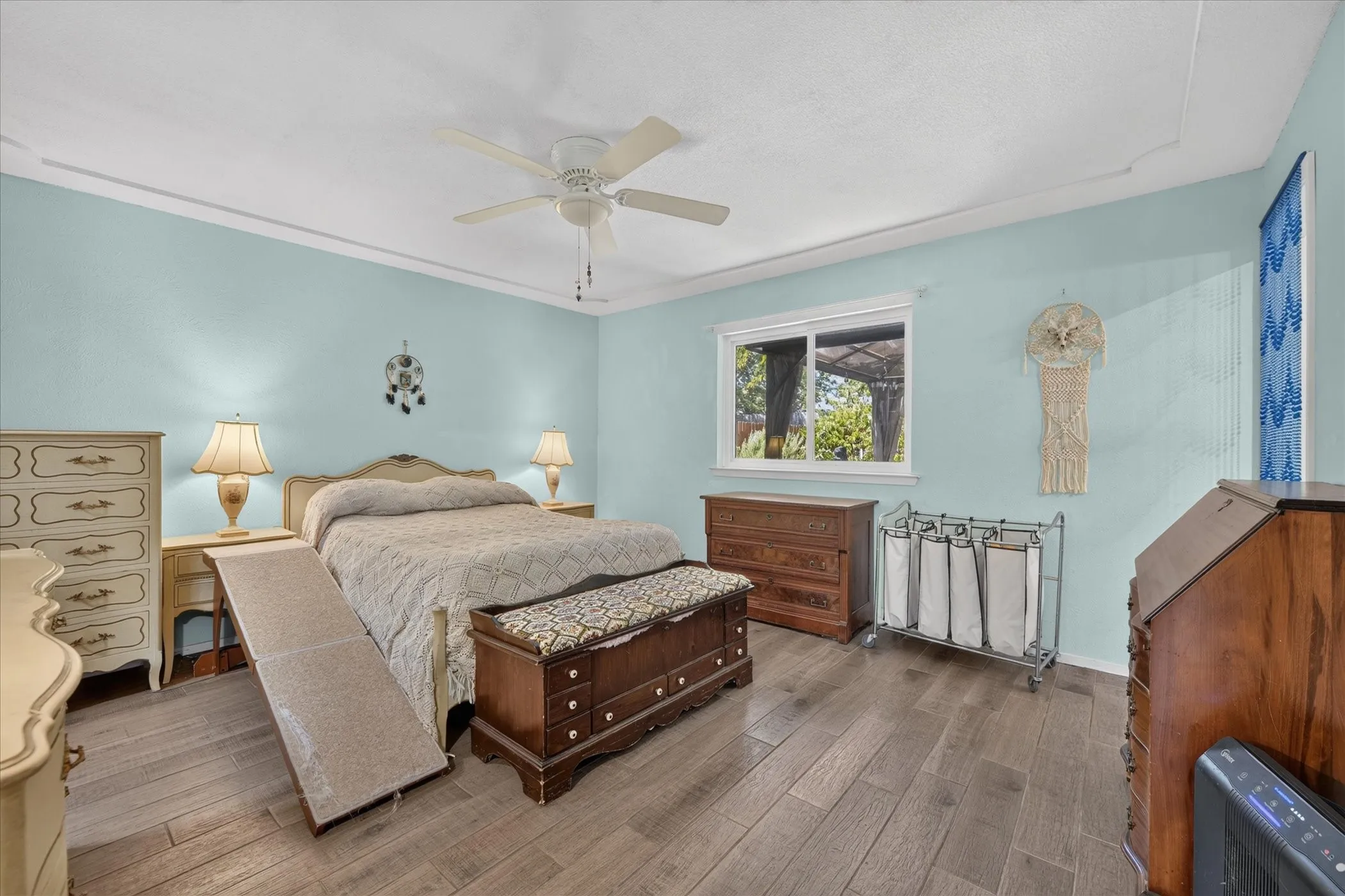 Recessed ceiling with crown molding, ceiling fan, wood-finish flooring, and a large window
