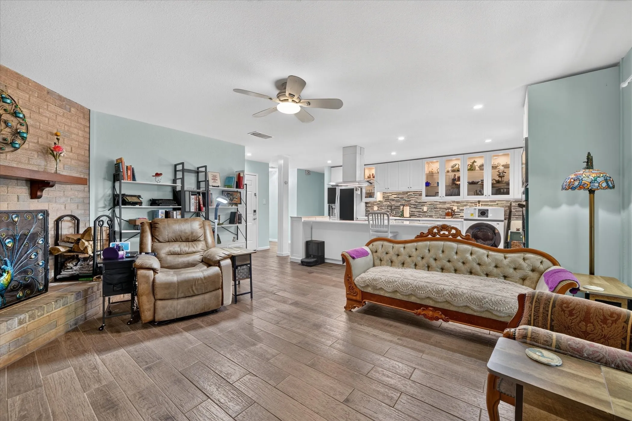 Wood-finish flooring throughout, with a brick-clad fireplace and wood mantel