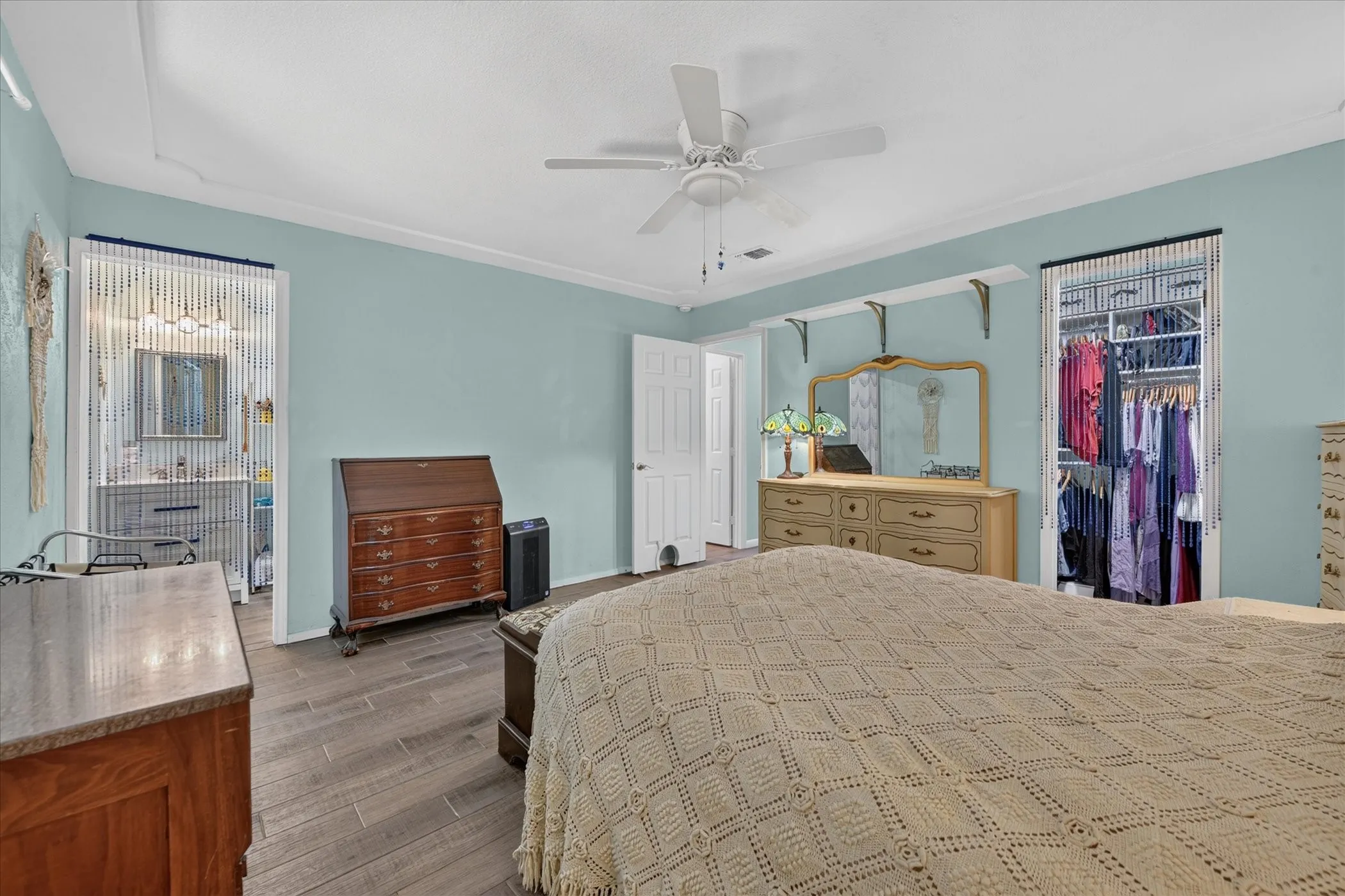 Spacious room featuring wood-finish flooring, a ceiling fan, and built-in closet organization