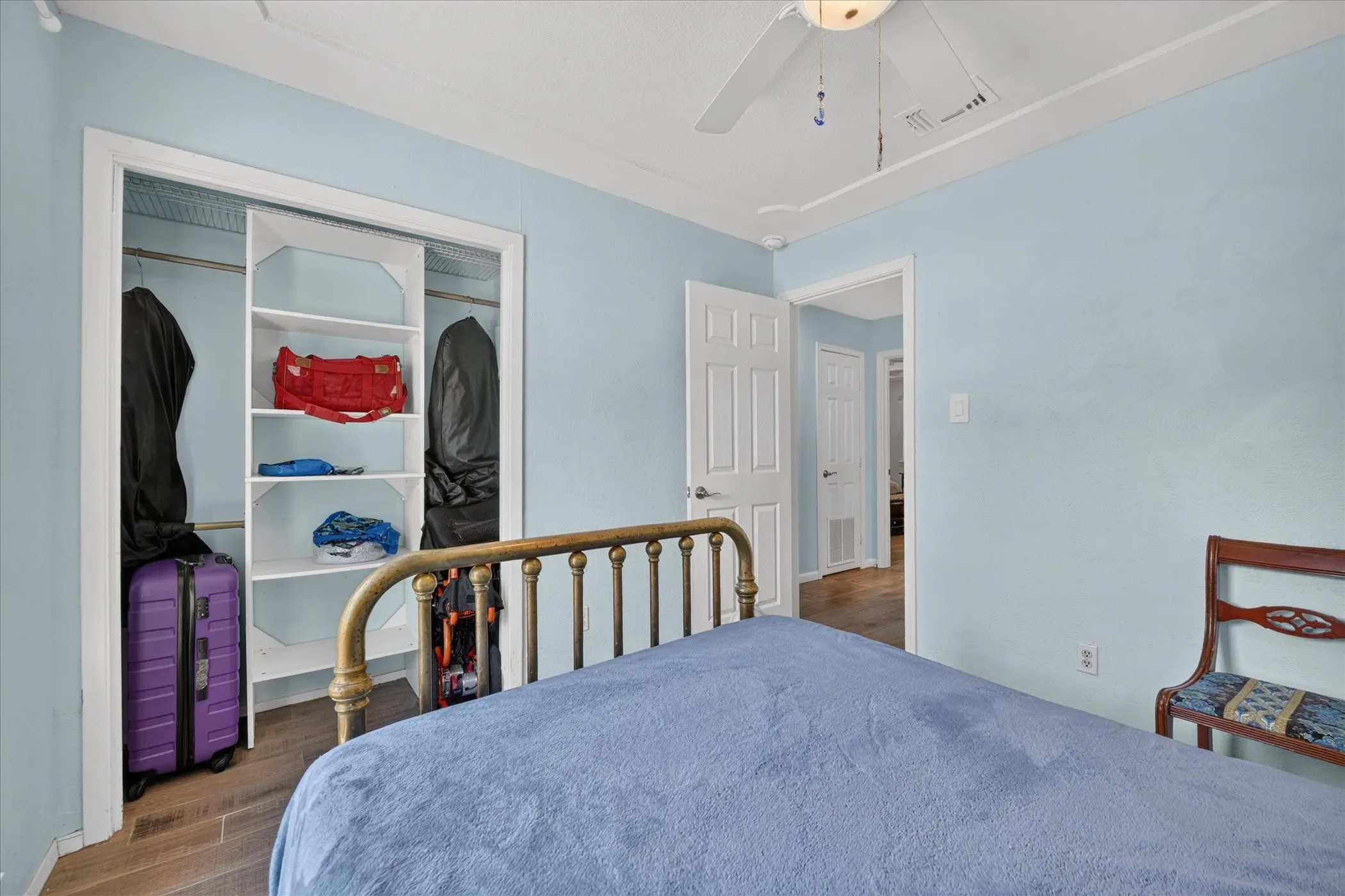 Built-in closet shelving and hanging rods, overhead ceiling fan, and wood-finish flooring