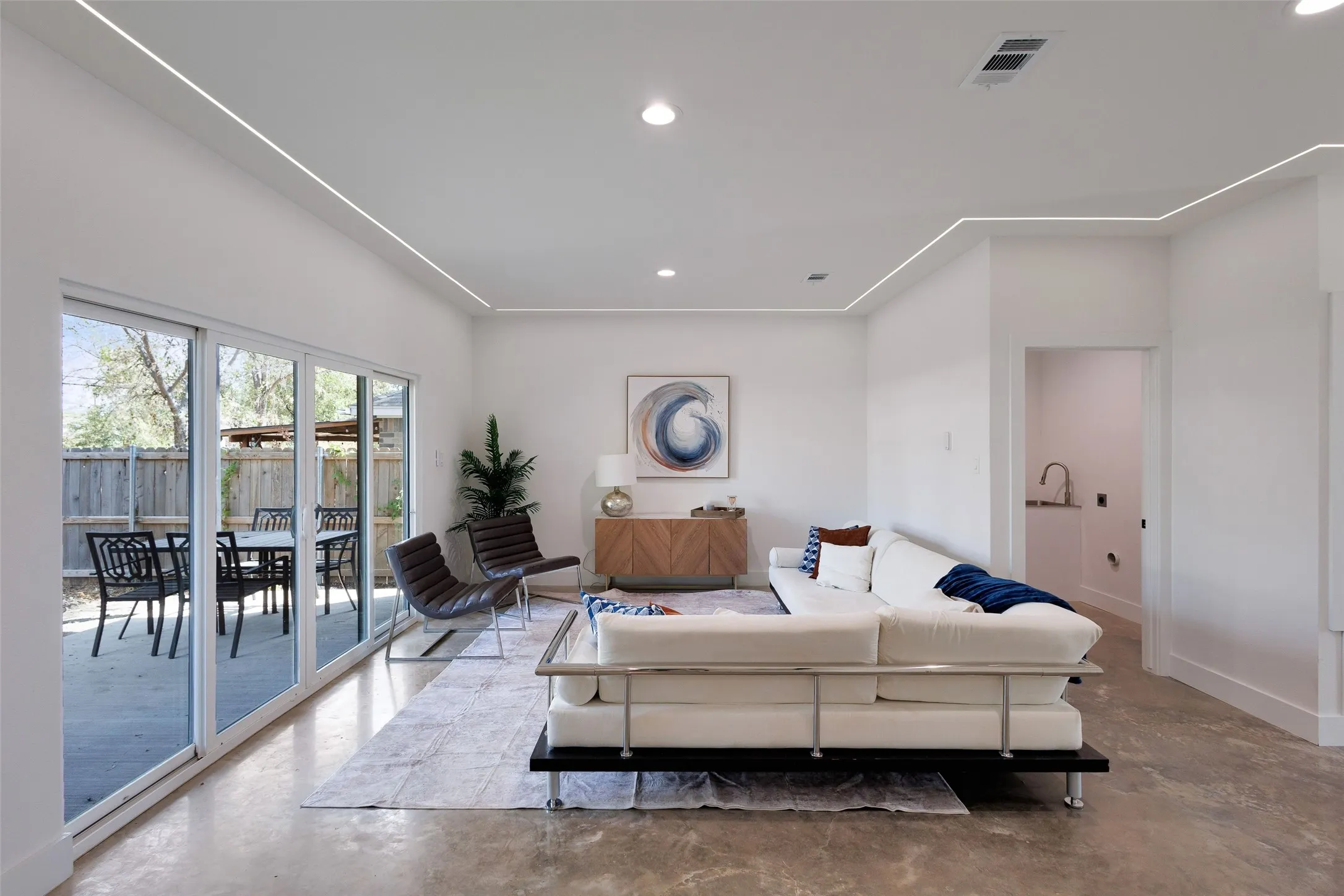 Spacious living area featuring polished concrete flooring and recessed linear lighting