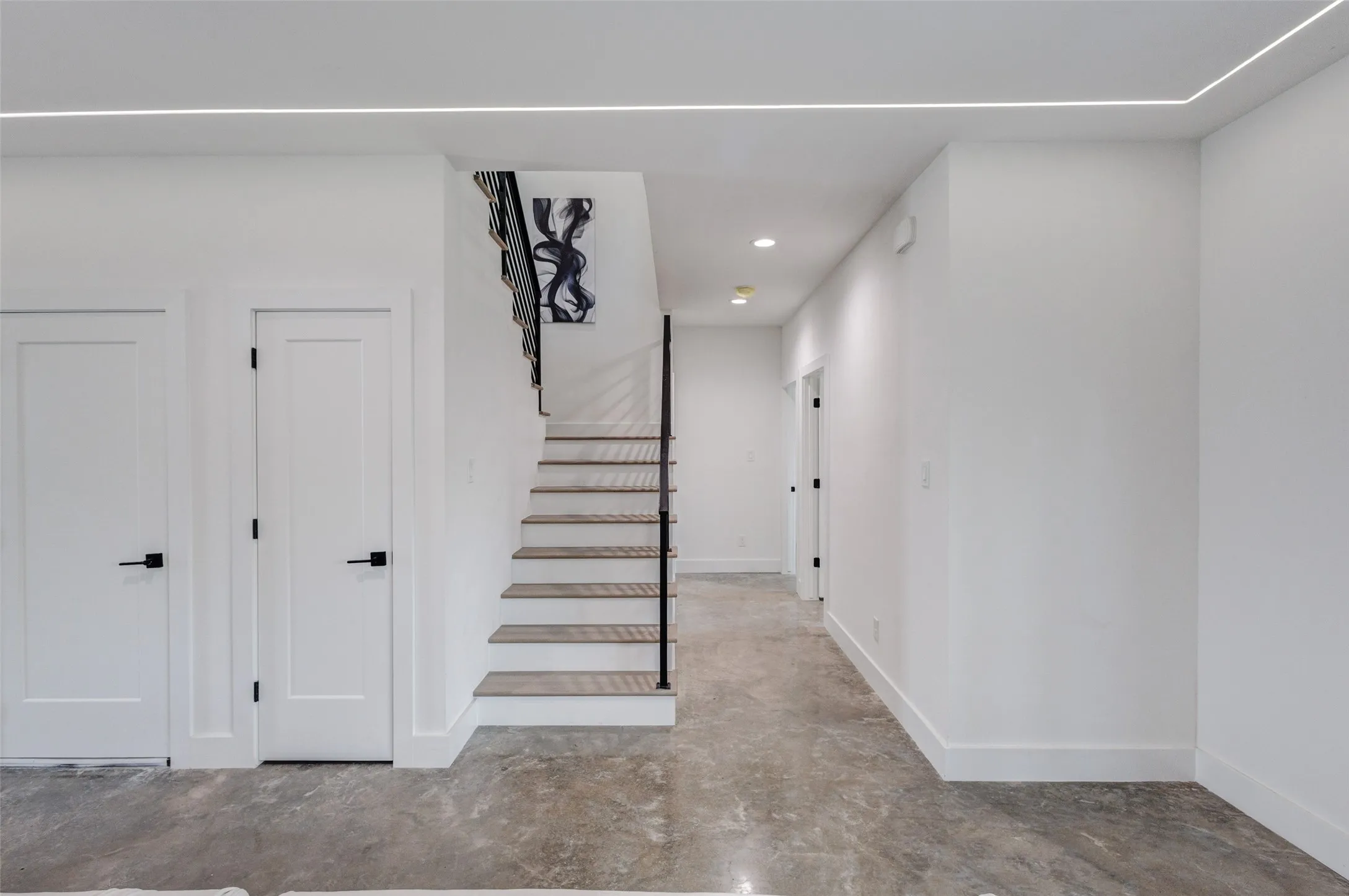 Modern interior with concrete-finish flooring, white walls, and recessed lighting