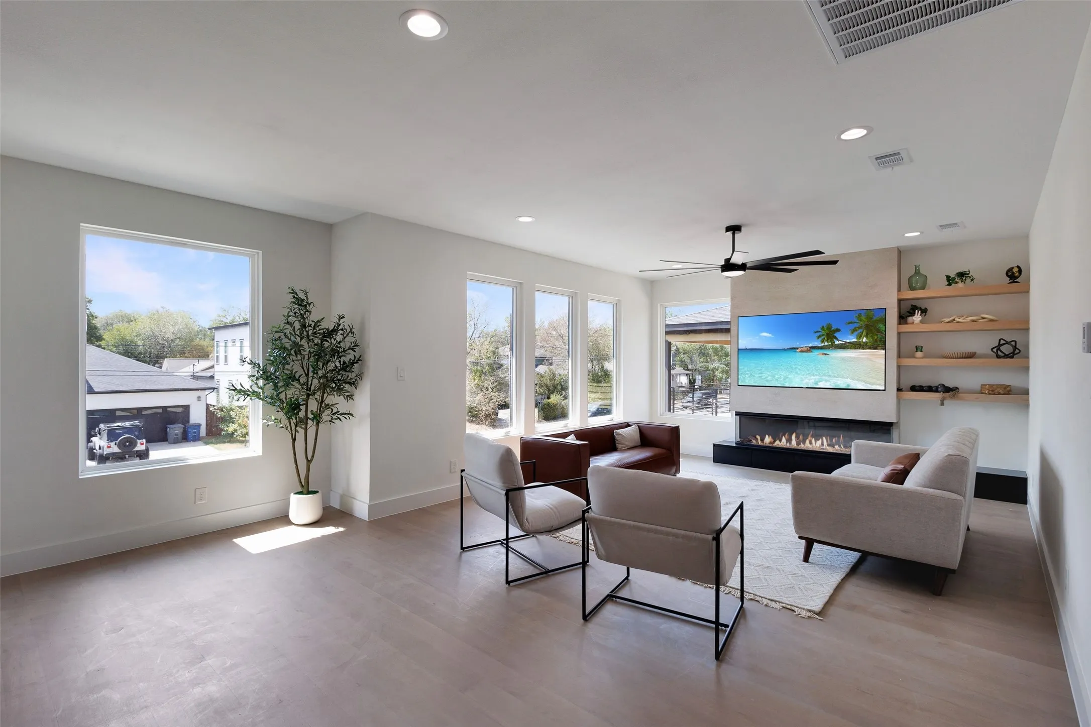 Expansive living area with wood-finish flooring, recessed lighting, and a modern ceiling fan