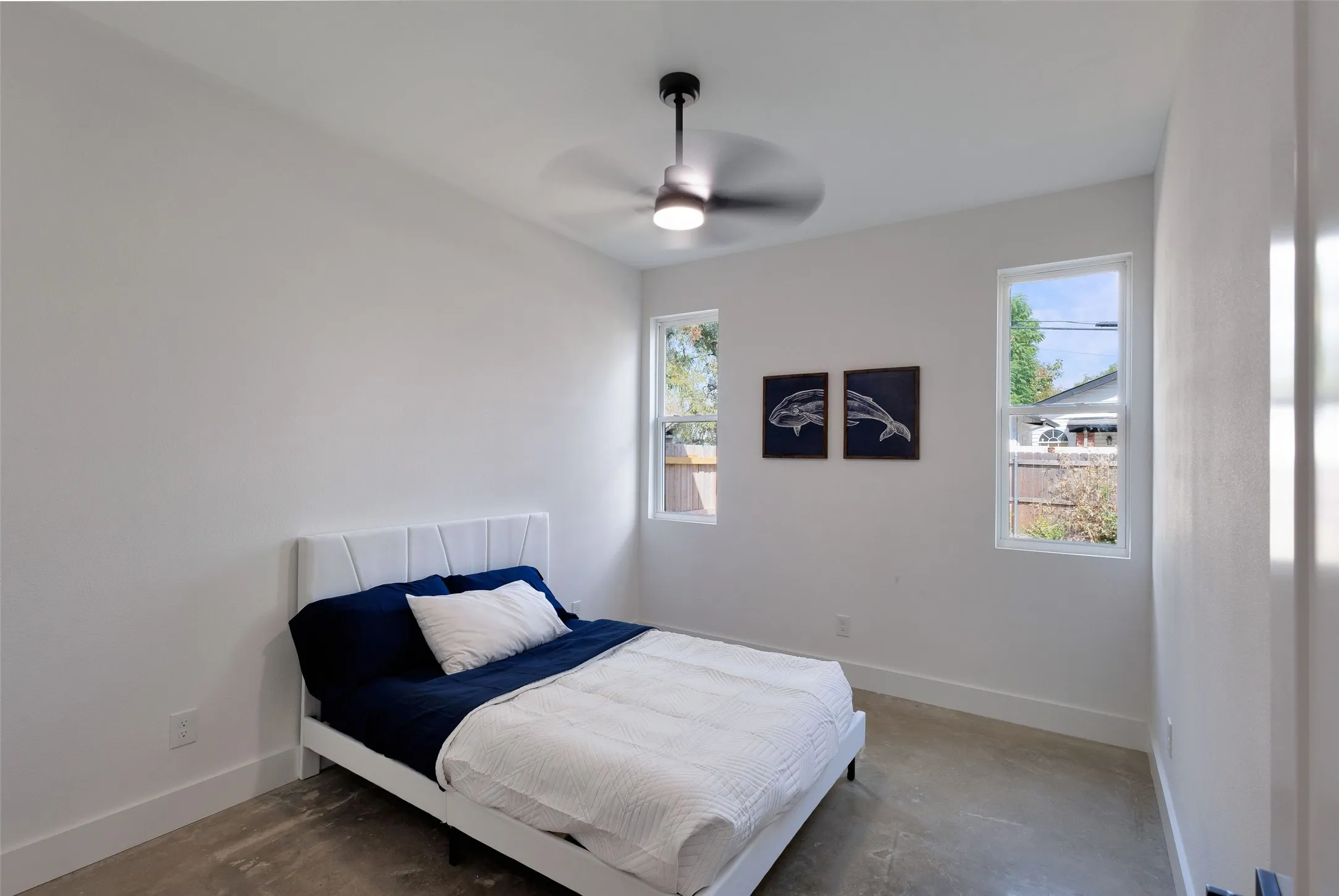 Recessed lighting, ceiling fan with integrated light, two windows, and concrete flooring