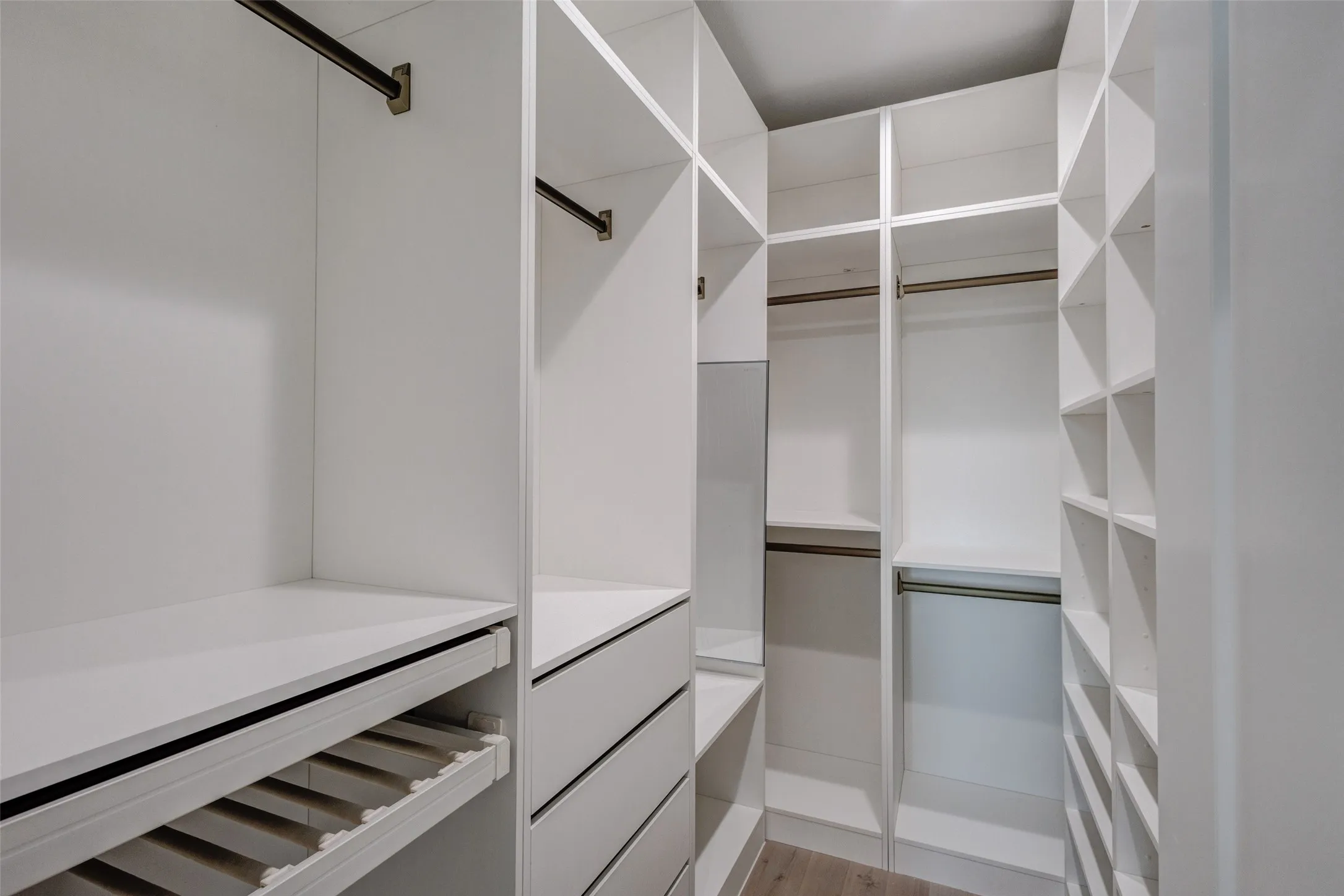 Custom closet system with multiple hanging rods, integrated drawers, diverse shelving, and dedicated shoe storage