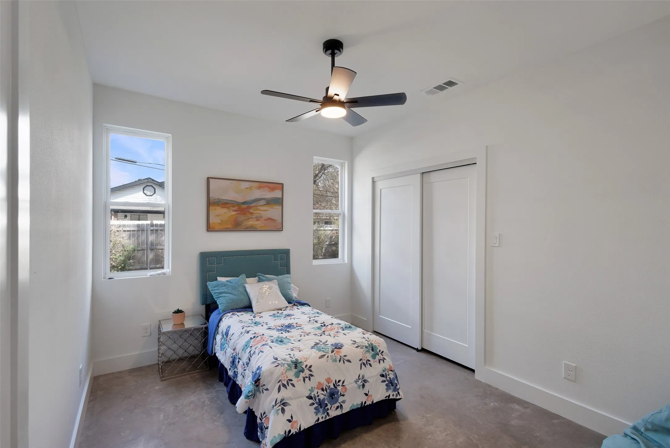 White walls and ceiling, two vertical windows, modern ceiling fan, and sliding closet doors