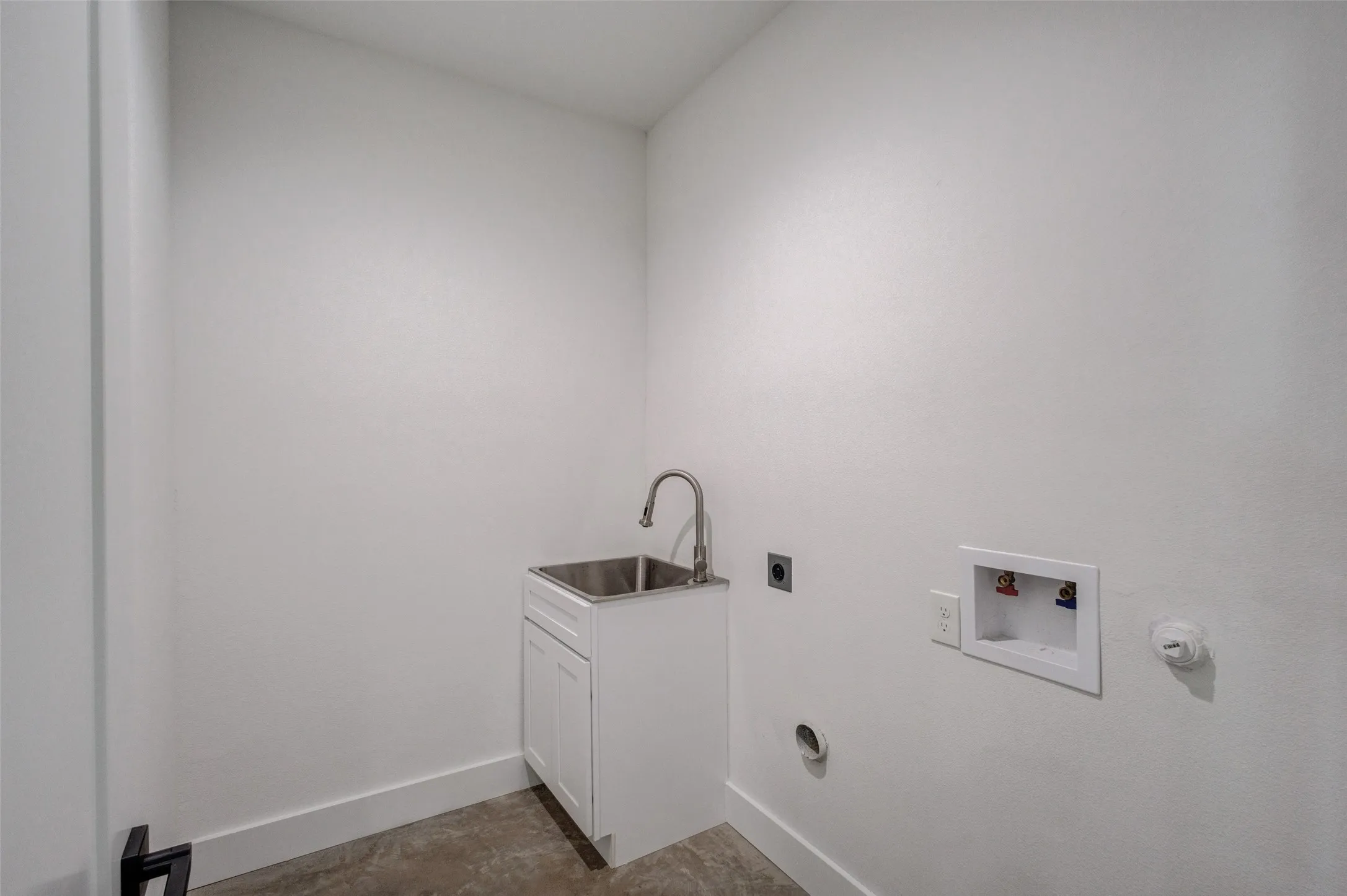 Utility sink with stainless steel basin, single-handle faucet, and white base cabinet