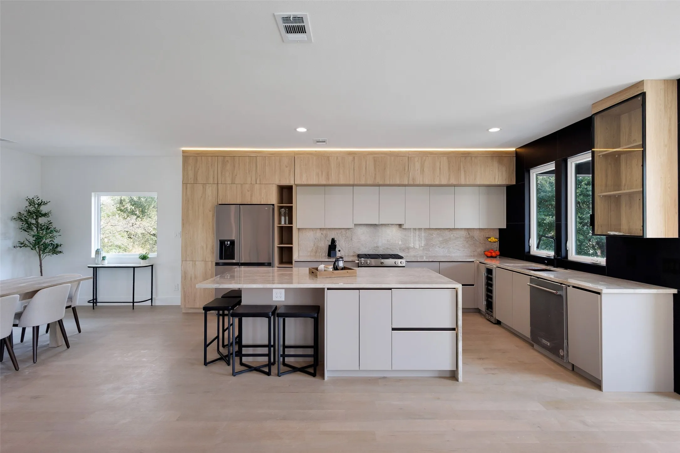 Open-concept kitchen featuring light wood-finish flooring, a large center island with integrated seating, and stainless steel appliances