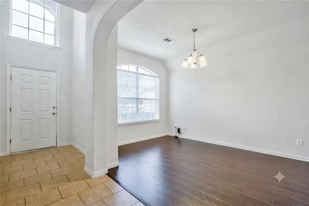 Two-story entry with arched window, decorative front door, and tile flooring