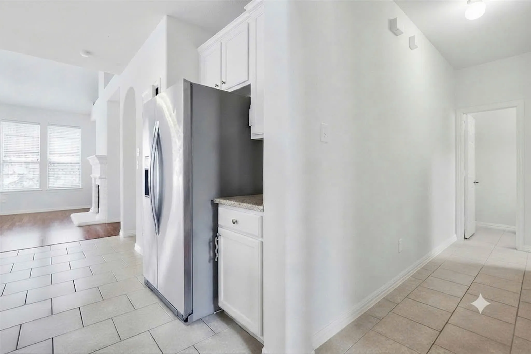 Kitchenette with white cabinetry, stainless steel refrigerator, and light-toned countertops