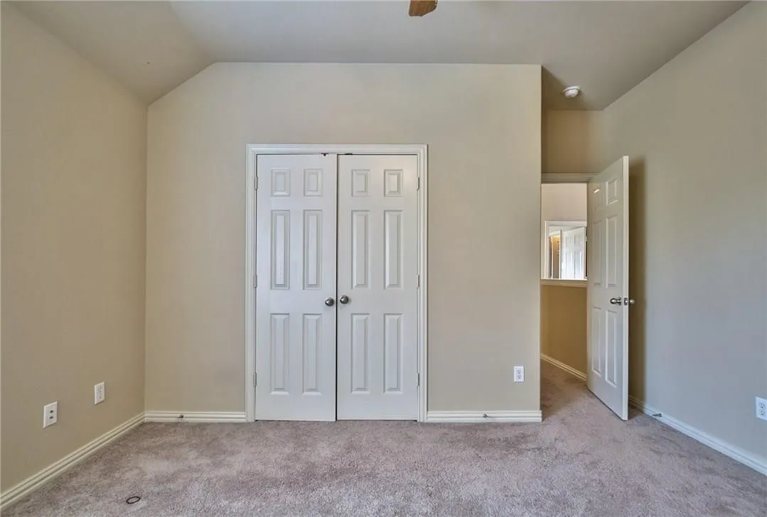 Vaulted ceiling, neutral wall paint, white trim, paneled interior doors, and carpet flooring